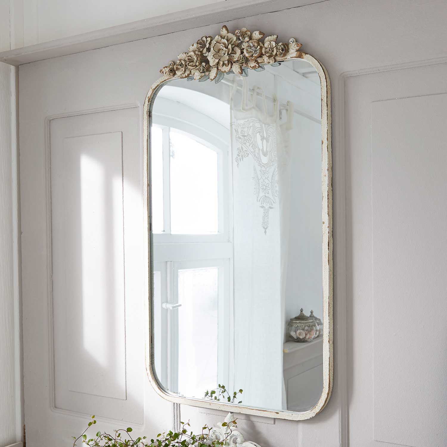 Wandspiegel met versierde lijst van wit verweerd hout met bloemenpatroon in vintage stijl