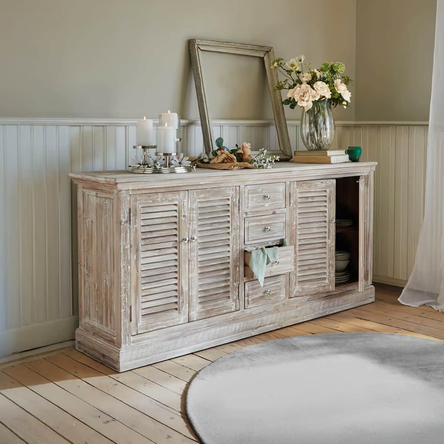 Rustieke houten dressoir met witte verweerde afwerking, versierd met kaarsen en bloemen in woonkamer
