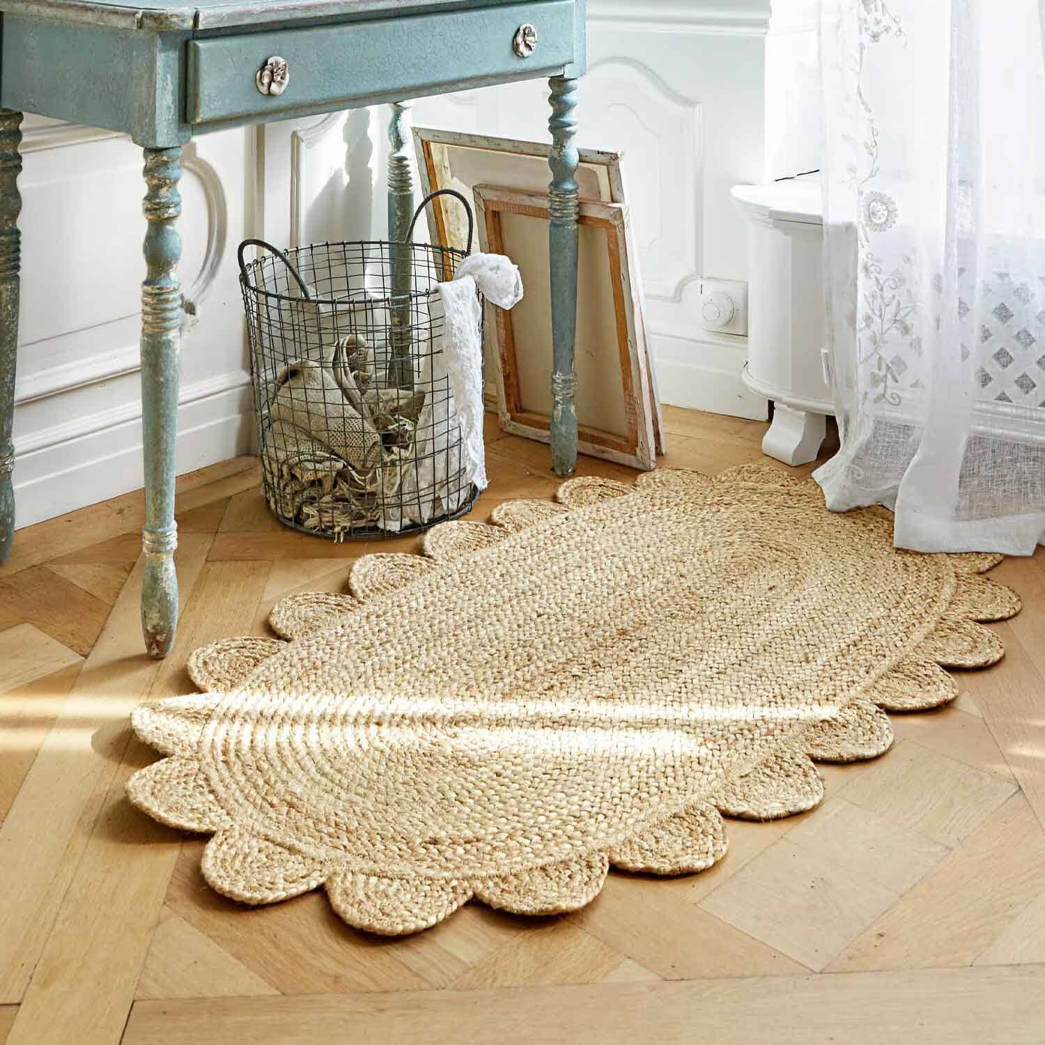 Ovale jute vloerkleed in natuurlijke kleur met decoratieve gegolfde rand op lichte houten vloer