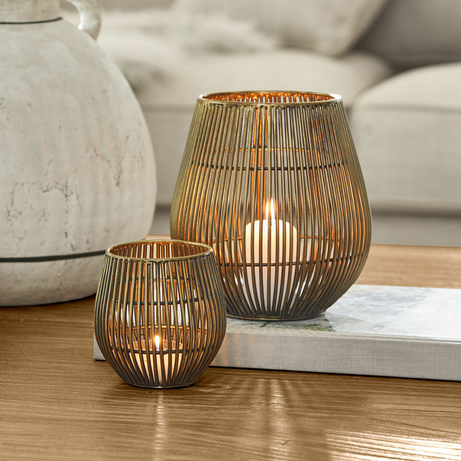 Windlicht set van 2 Pontarino Twee messingkleurige metalen lantaarns met verticale staven en brandende kaarsen binnenin, tafeldecoratie