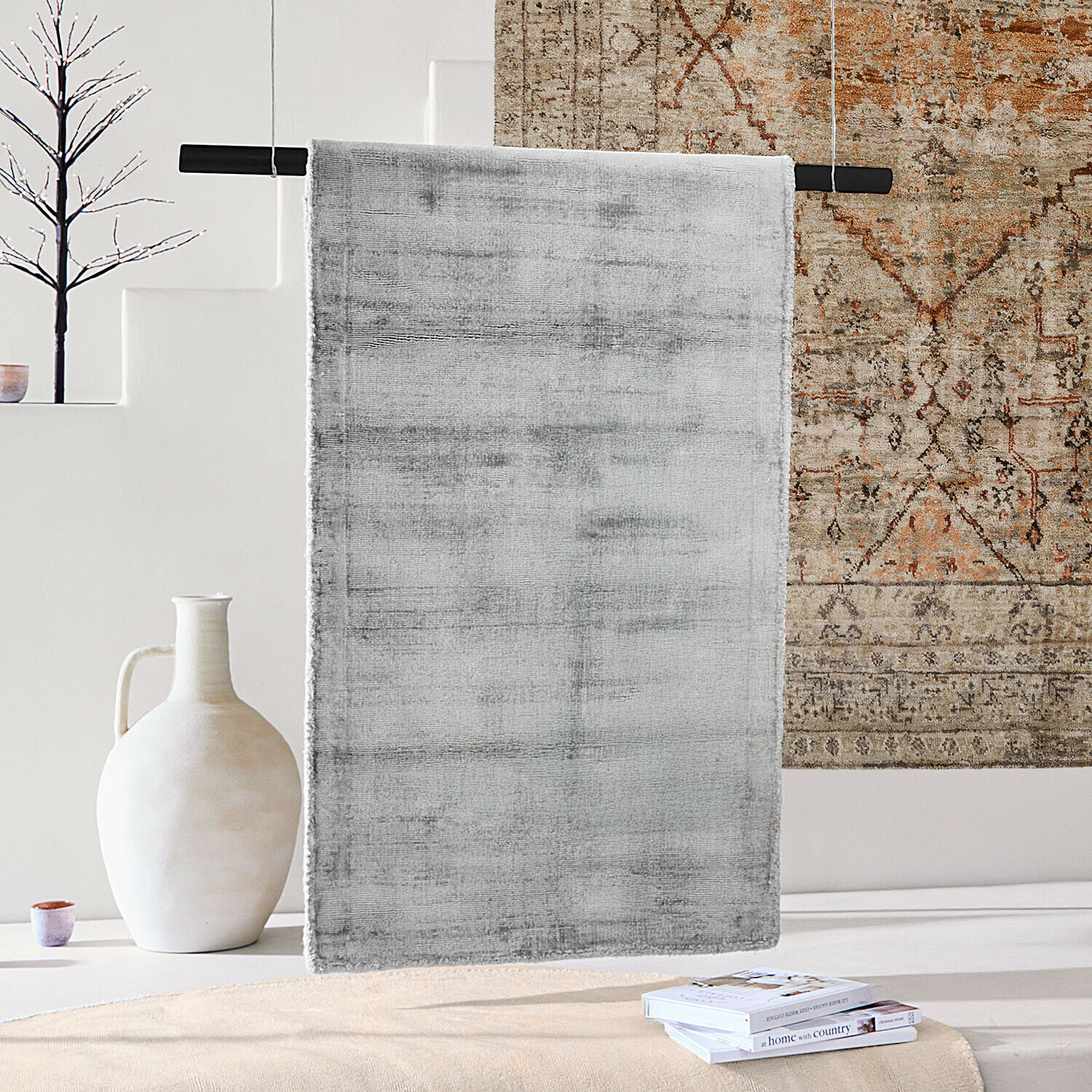 Grijs vloerkleed van zacht materiaal in modern interieur met decoratieve vaas en boeken