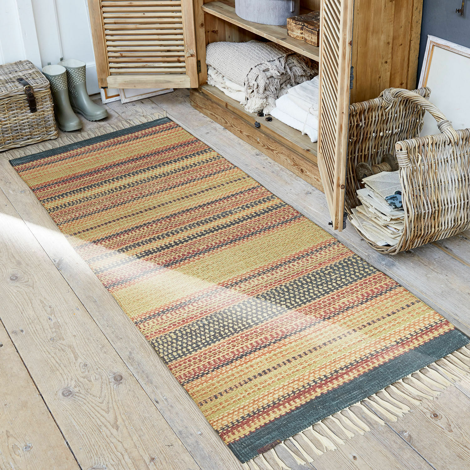 In- & outdoor loper Atlanta Gestreept vloerkleed in warme kleuren met franjes op houten vloer in rustieke ruimte