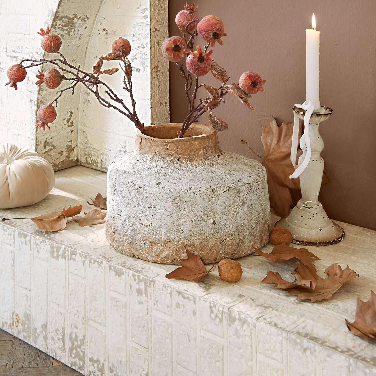 Rustieke beige keramische vaas met gedroogde granaatappels en herfstbladeren als decoratie