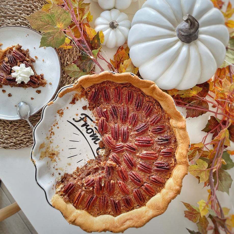 Pecannotentaart op bord met herfstdecoratie en witte pompoenen