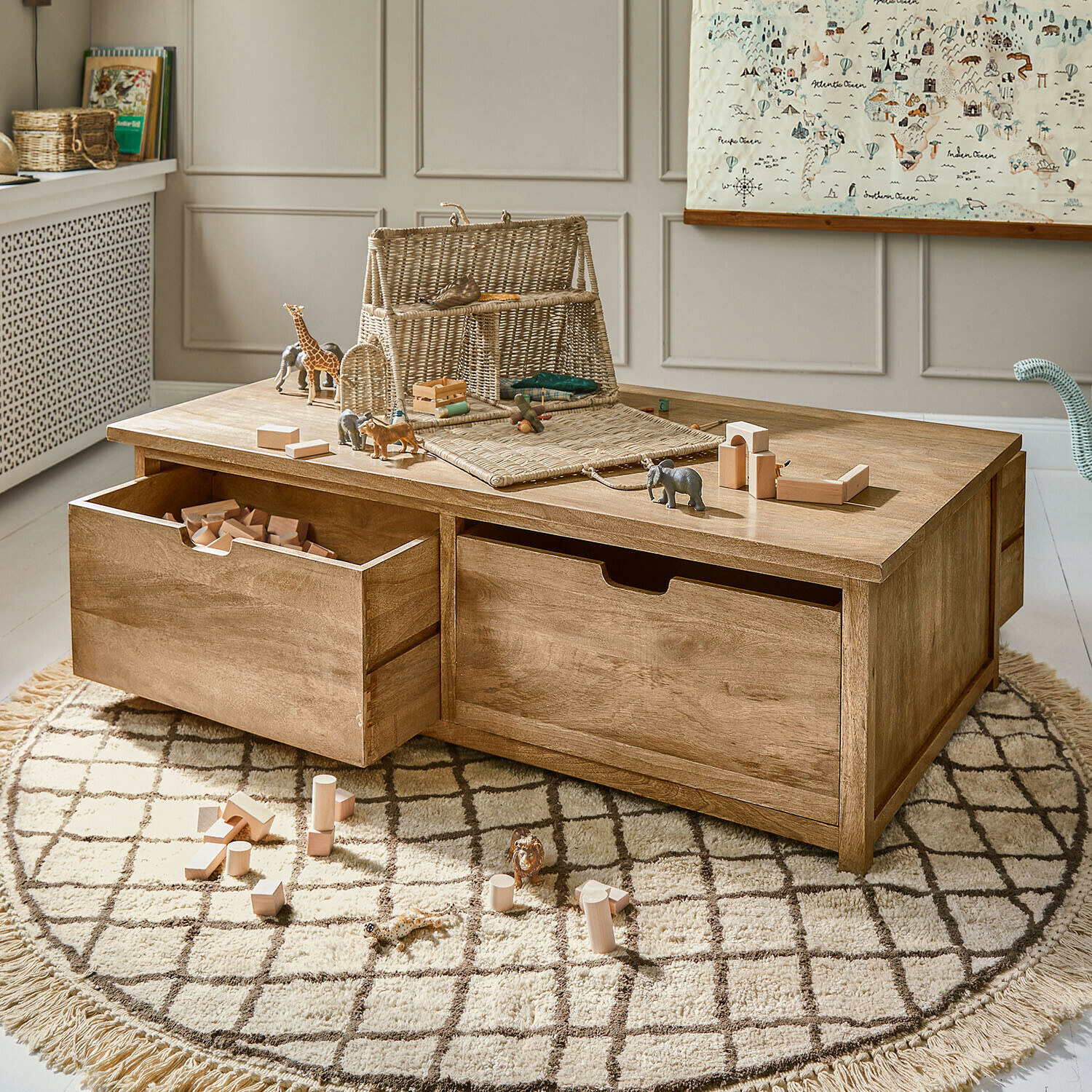 Houten salontafel met lades en speelgoed op ronde vloerkleed in lichte kinderkamer