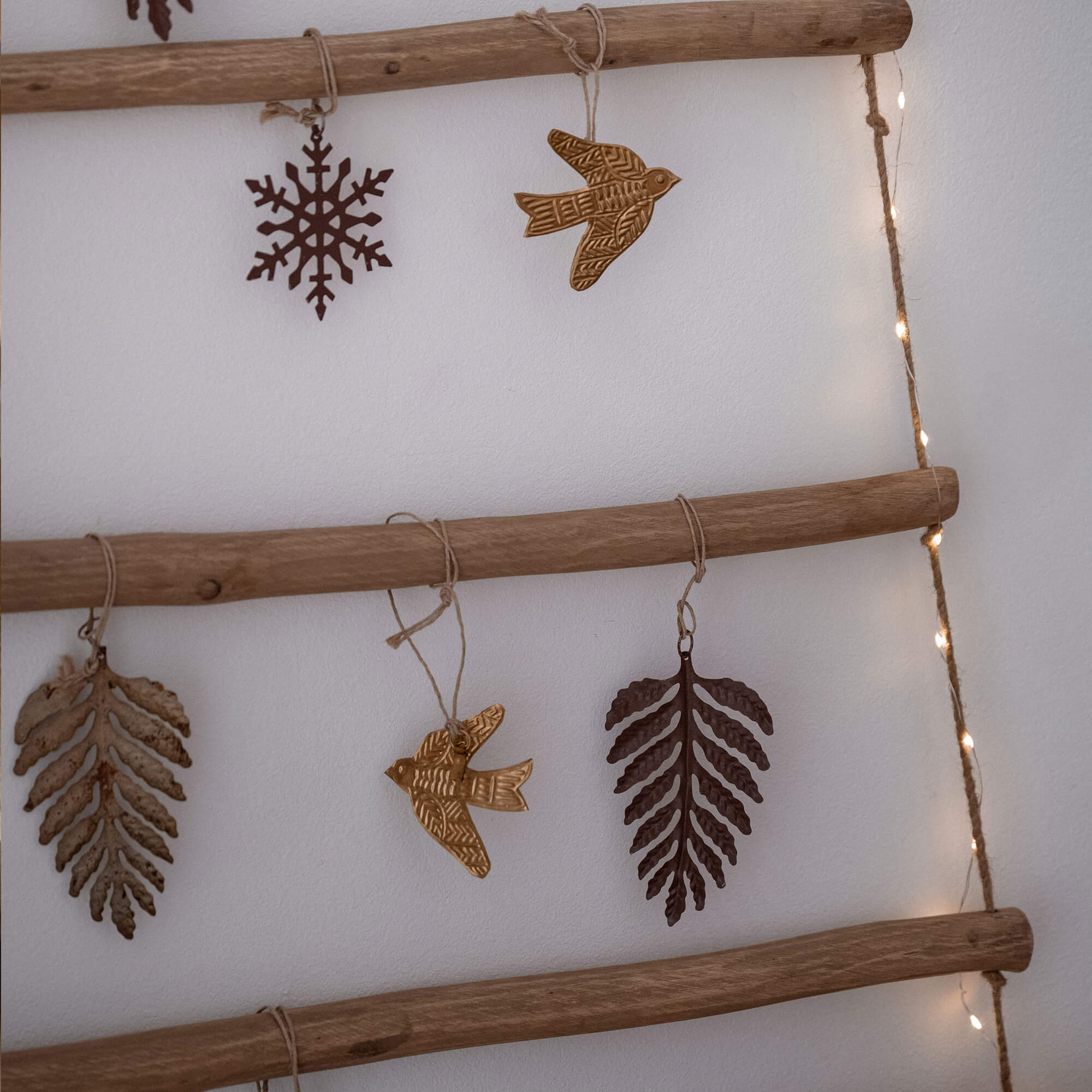 Houten wanddecoratie met metalen hangers in de vorm van bladeren, vogels en sneeuwvlokken