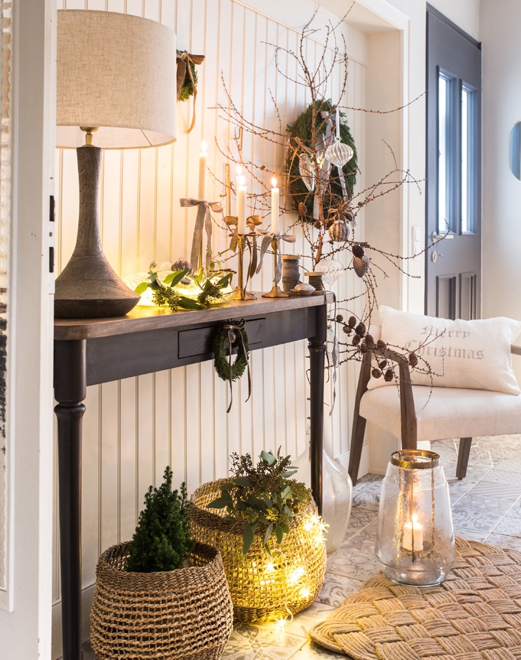 Gezellige hal met zwarte houten tafel, lamp en natuurlijke kerstdecoraties in warm licht