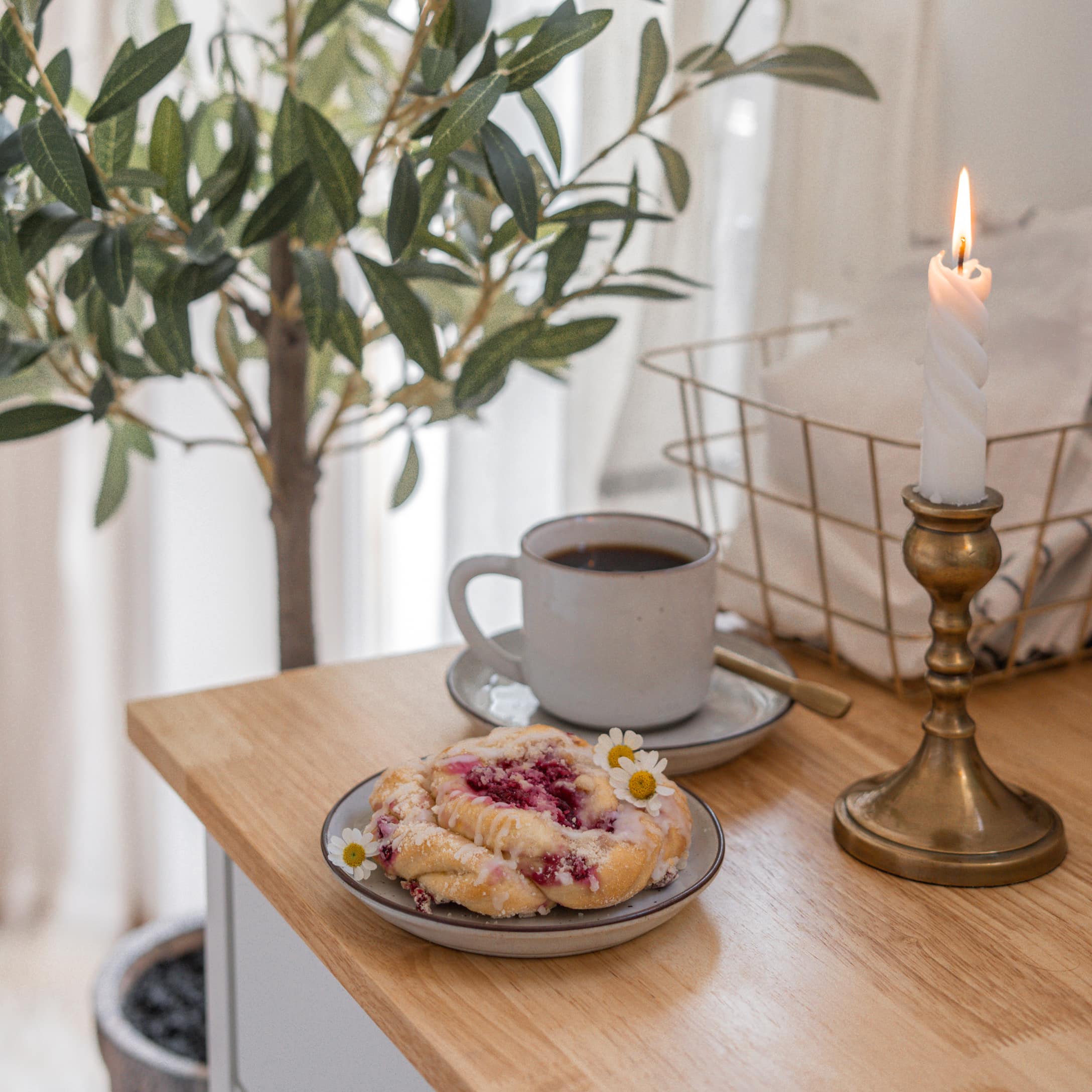 Gedraaide messing kandelaar op houten tafel met kop koffie en fruitgebakje