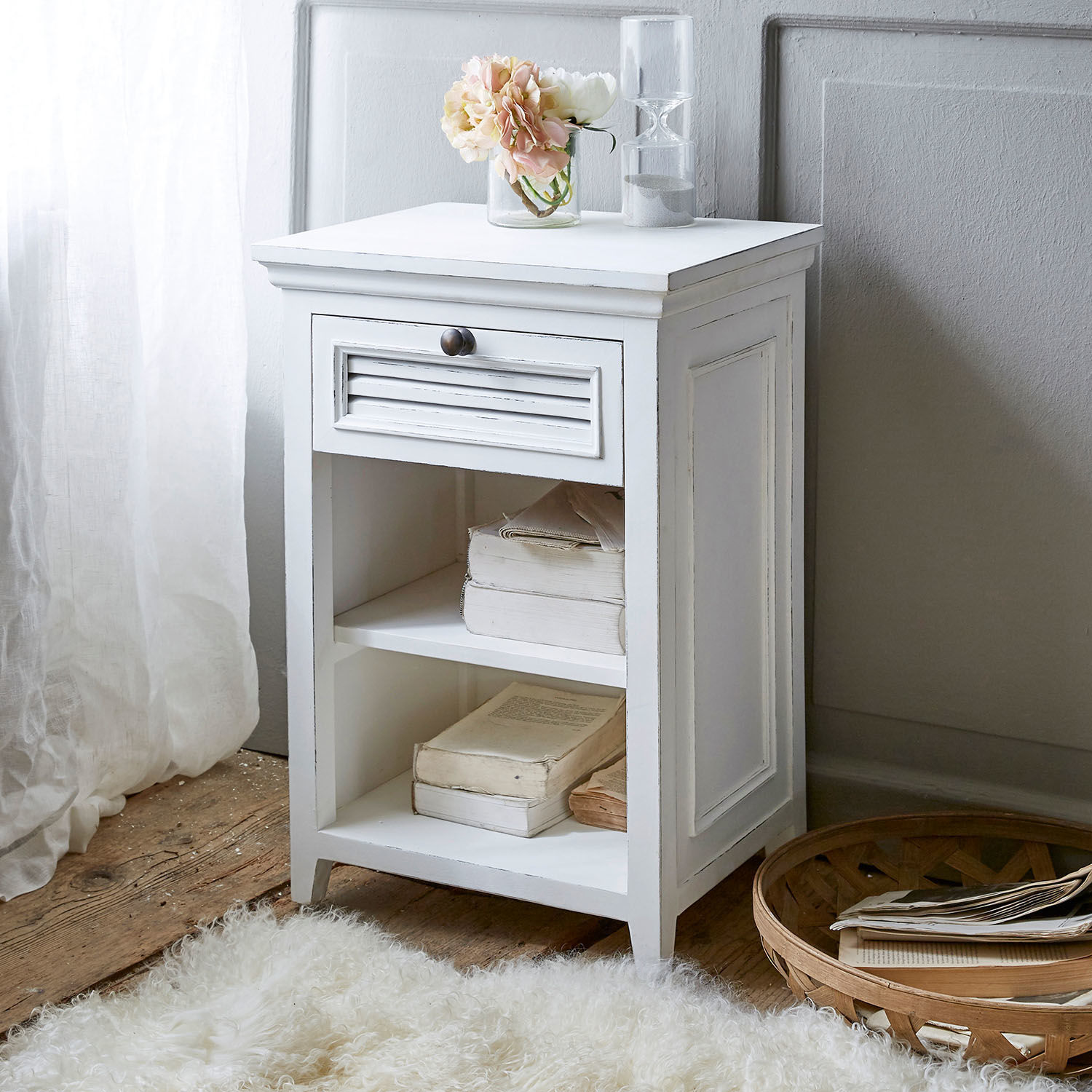 Witte houten nachtkastje met lade en planken, versierd met bloemen en zandloper