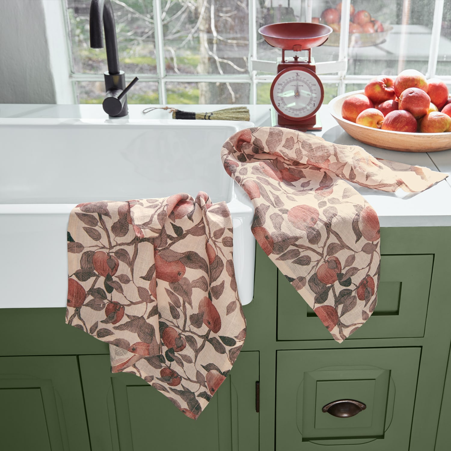 Linnen keukendoeken met rood appelmotief op groene kast in lichte keuken