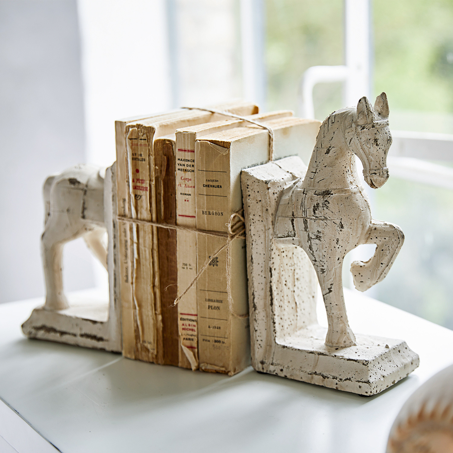 Boekensteun set van 2 Horses Witte keramische boekensteunen in paardenvorm met oude versleten boeken op tafel