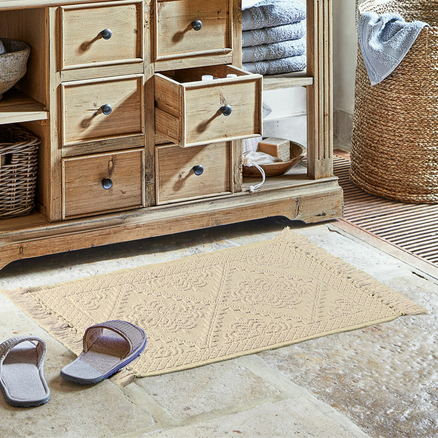 Badmat Mivorex Beige katoenen vloerkleed met franjes op stenen vloer bij houten kast in badkamer