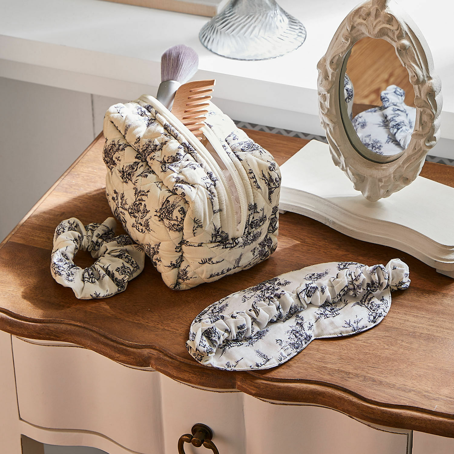 Slaapset 3-delig Felencio Beige gewatteerde make-uptas met zwart patroon, haarband en slaapmasker op houten tafel, verzorgingsaccessoires