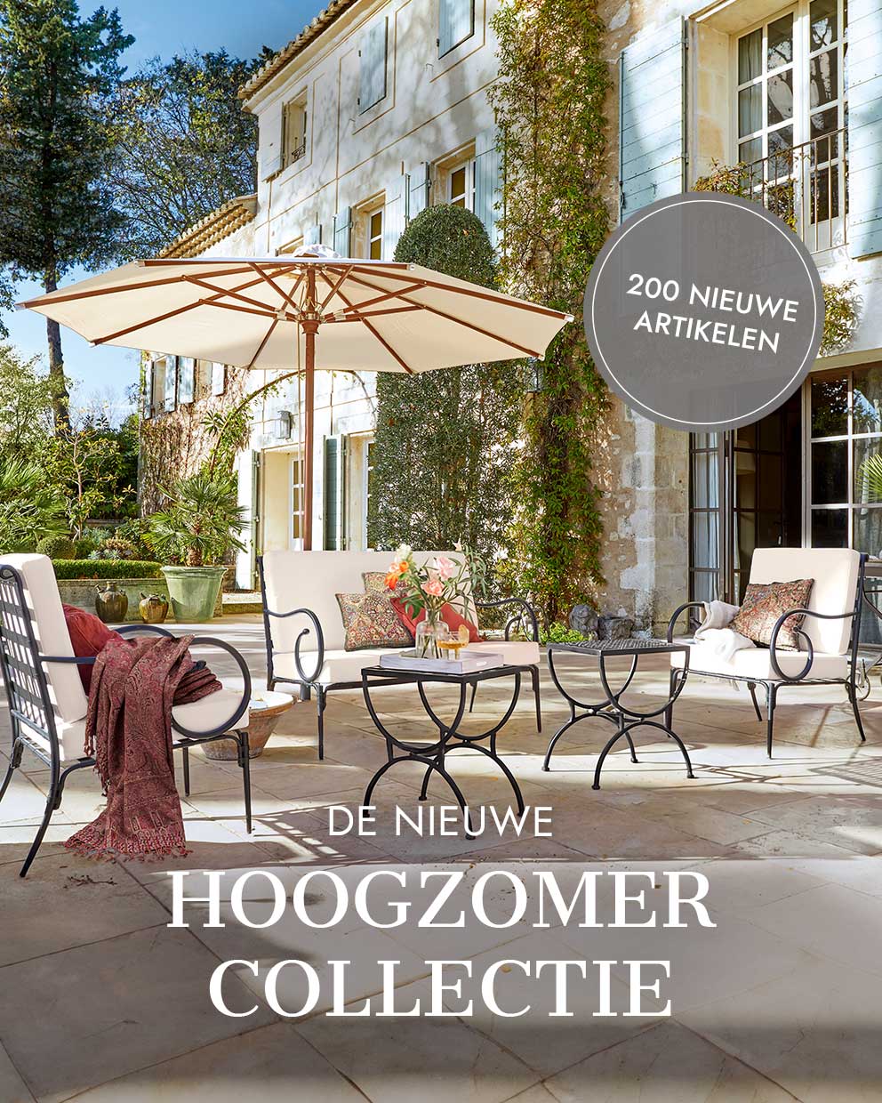 Tuinmeubelset met metalen frame en crèmekleurige kussens op zonnig terras met parasol