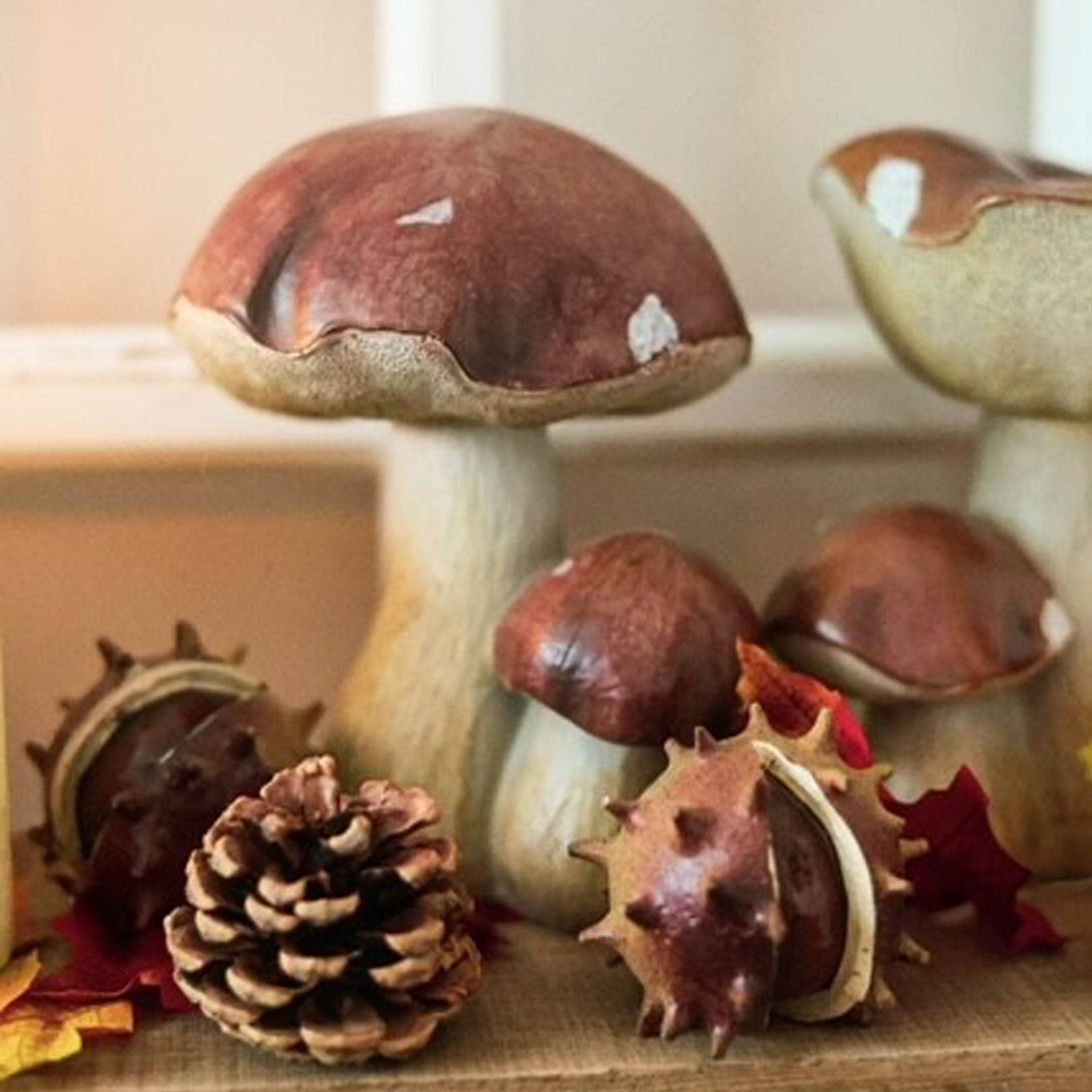 Decoratieve keramische paddenstoelen in bruin-beige tinten met dennenappel en kastanjes voor herfstdecoratie