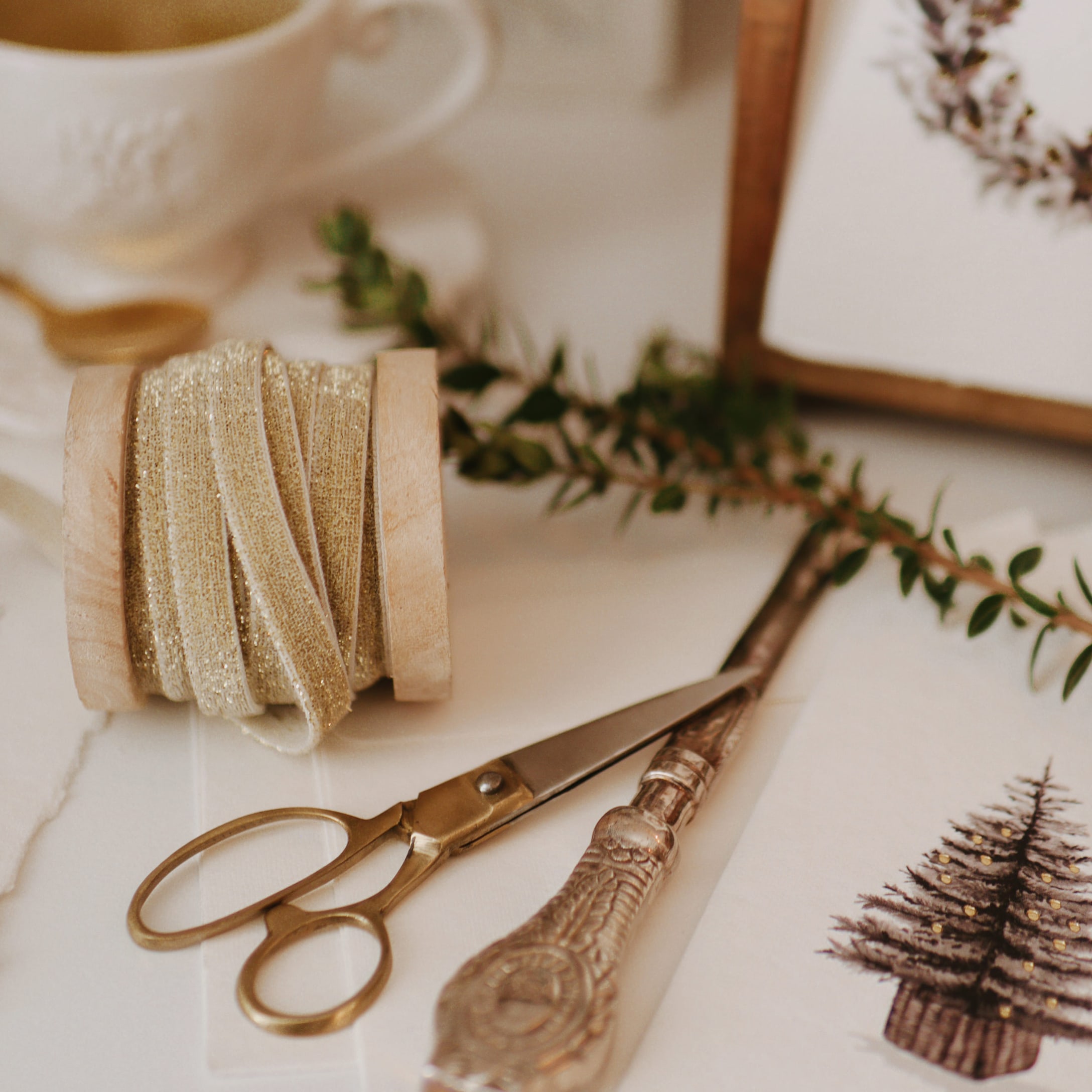 Gouden lint op houten spoel met schaar en kerstkaart met dennenboom op tafel