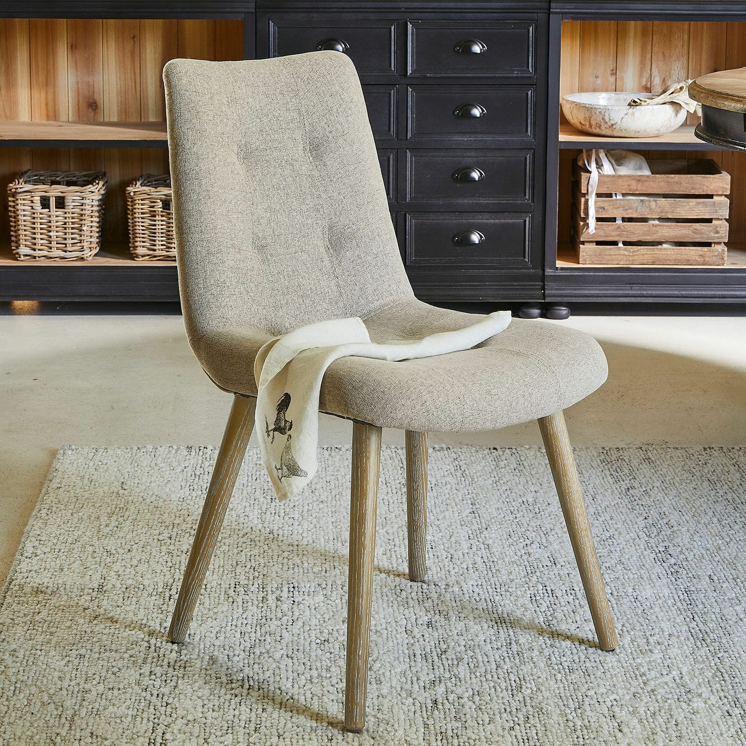 Beige gestoffeerde stoel met houten poten op tapijt in moderne kamer