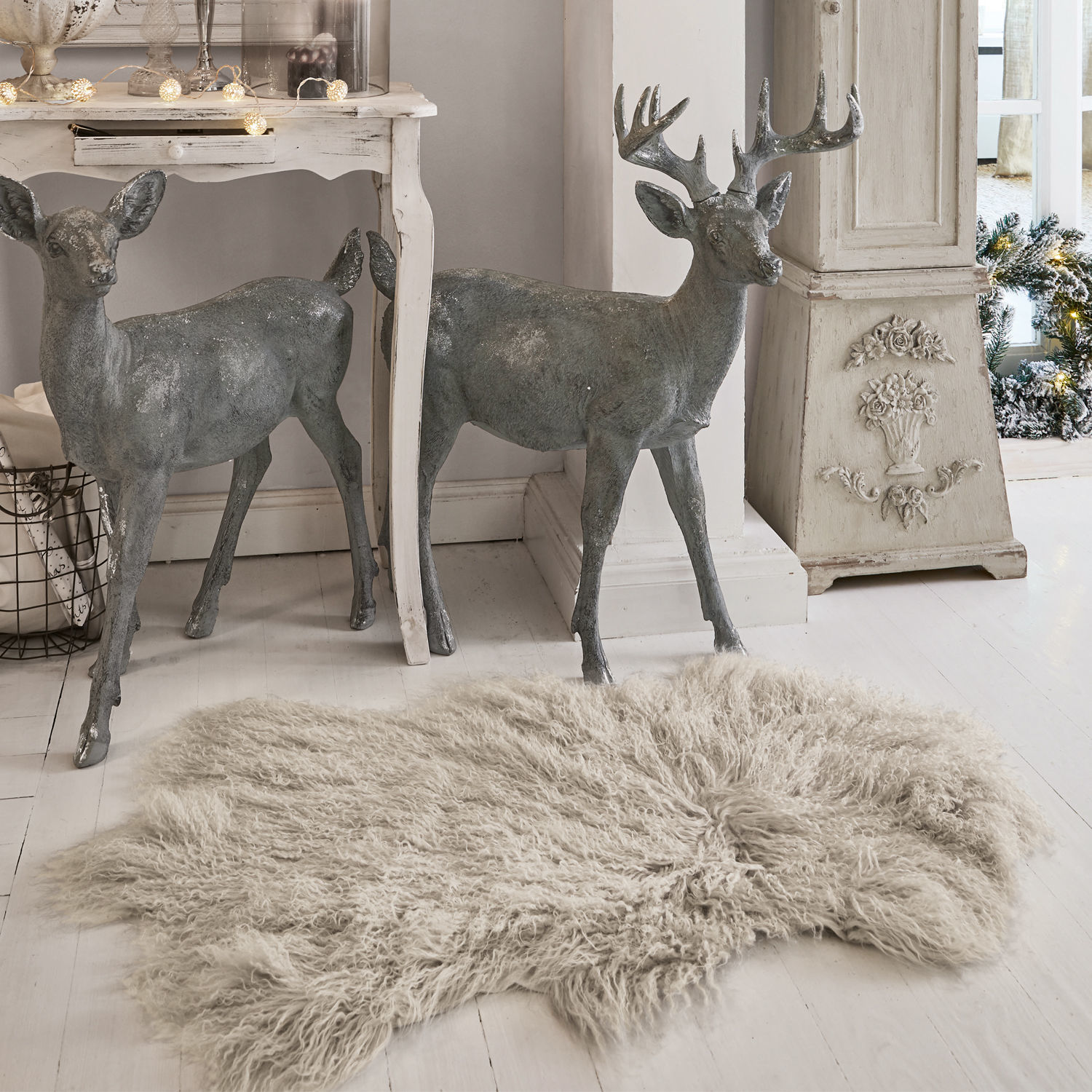 Lamsvacht Gad Grijze decoratieve metalen hertenfiguren naast witte tafel en beige langharig vloerkleed