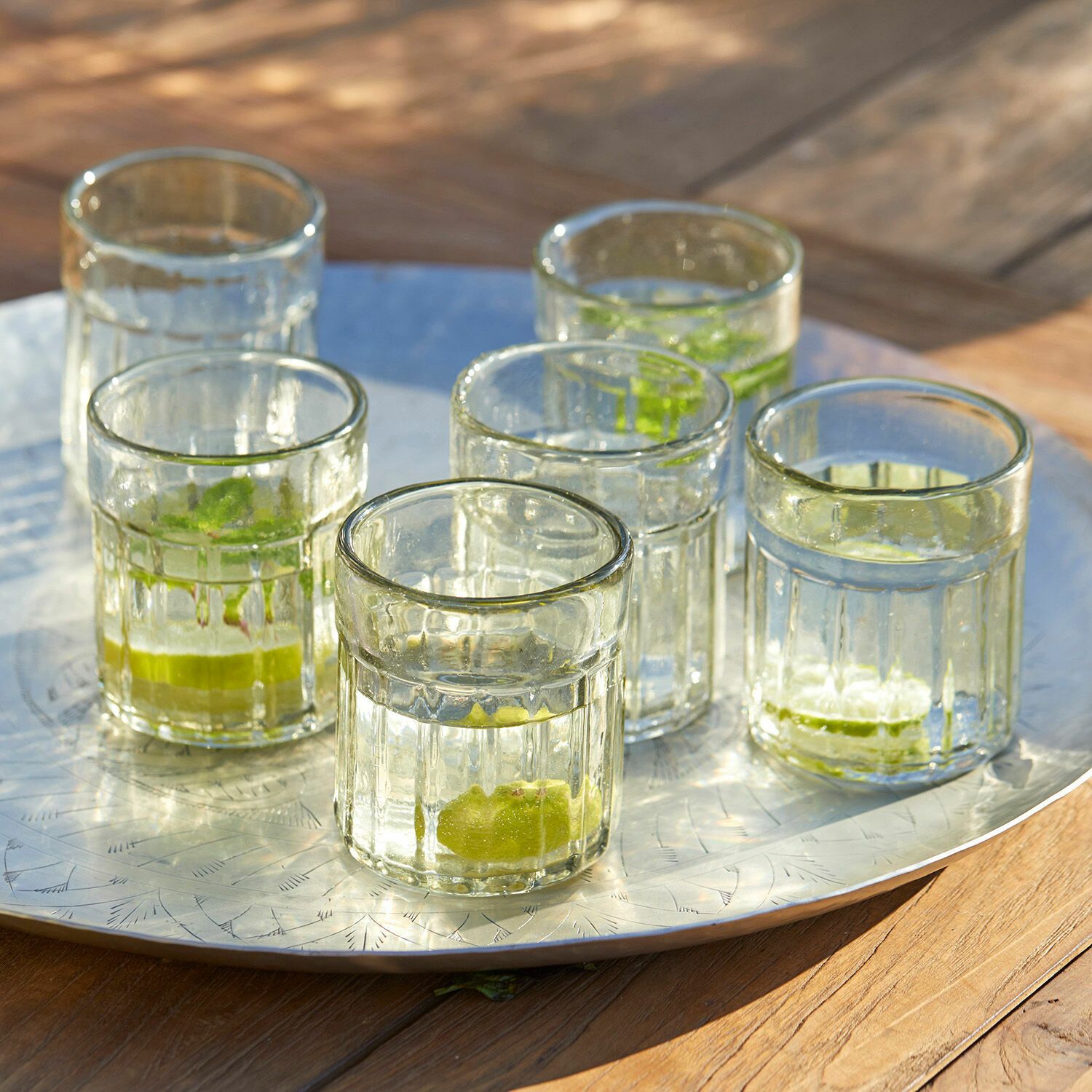 Zes doorzichtige glazen met limoen op een metalen dienblad op een houten tafel