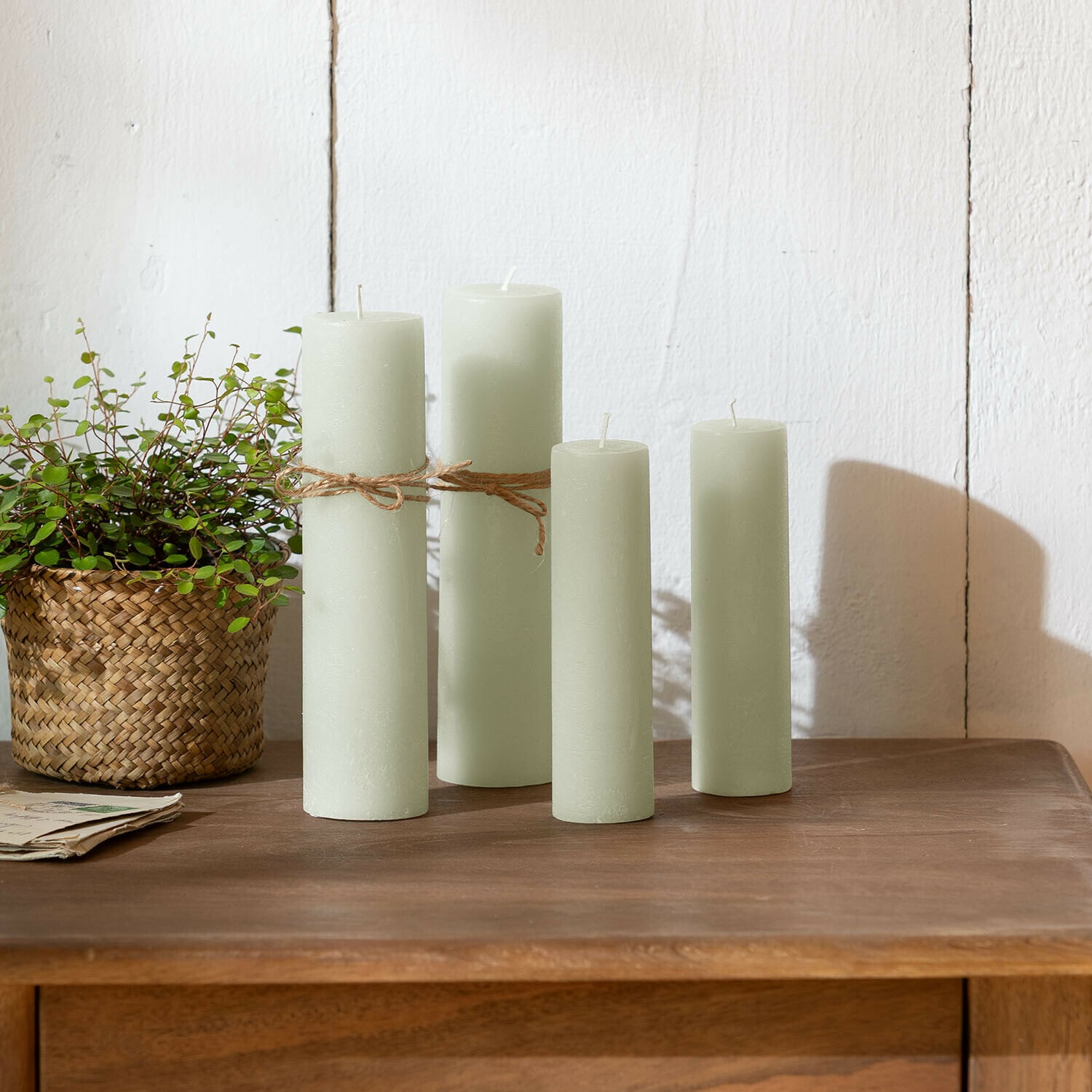 Kaars set van 4 Avinal Set van vier lichtgroene kaarsen van was op houten tafel met plant in gevlochten mand