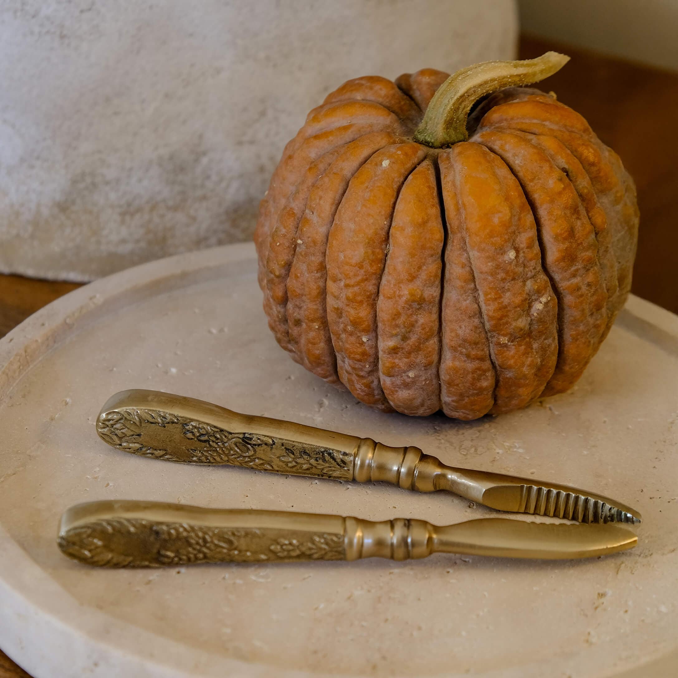 Set messing messen met versierde handvatten op beige dienblad naast oranje pompoen