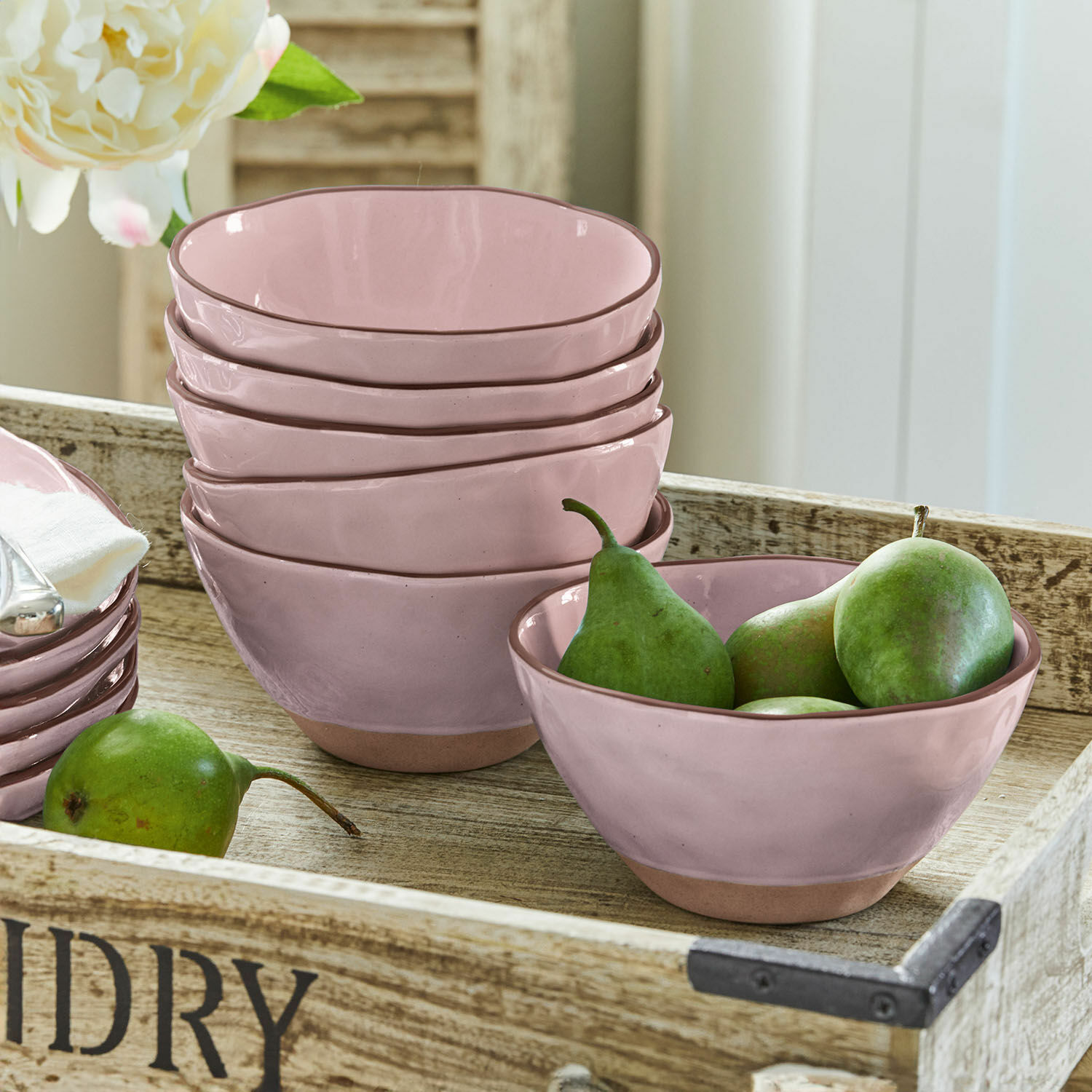Set roze keramische kommen met natuurlijke bruine bodem op houten dienblad met groene peren