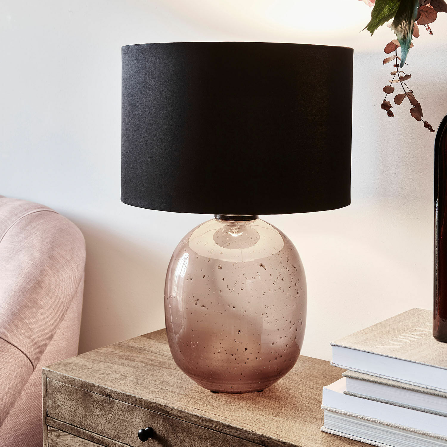 Tafellamp van bruin transparant glas met zwarte kap op houten tafel in woonkamer