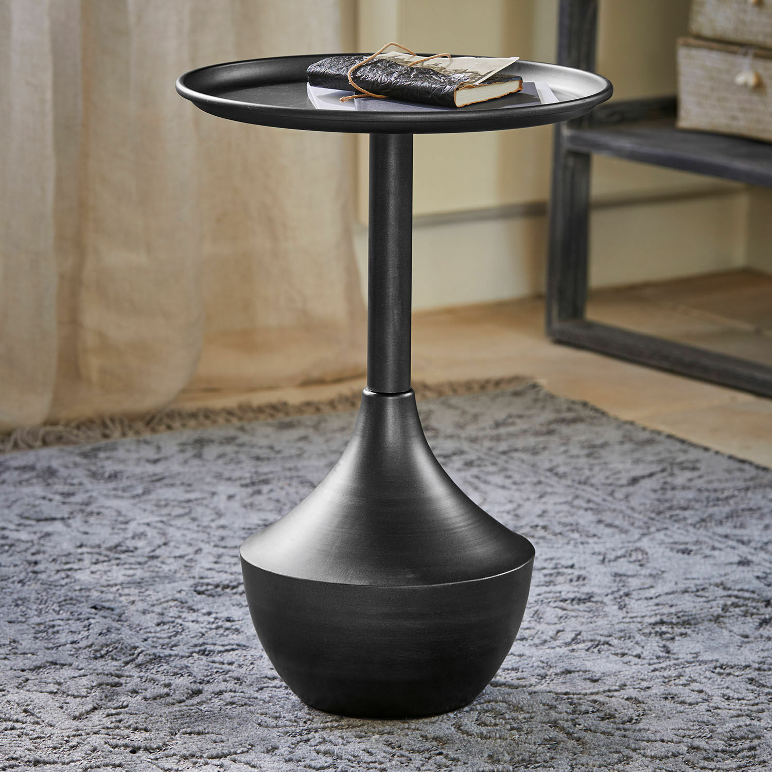Zwart metalen bijzettafel met modern design op een grijs tapijt in de woonkamer