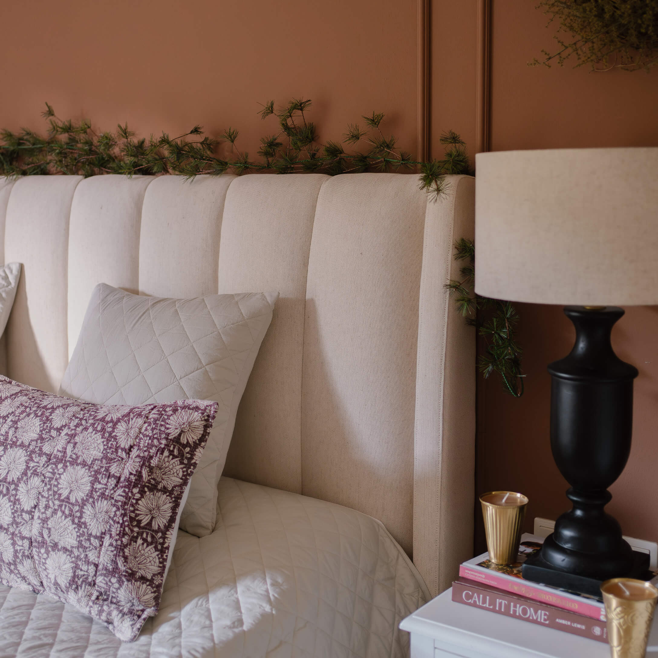 Beige gestoffeerd hoofdeinde met kussens en lamp op nachtkastje in een gezellige slaapkamer