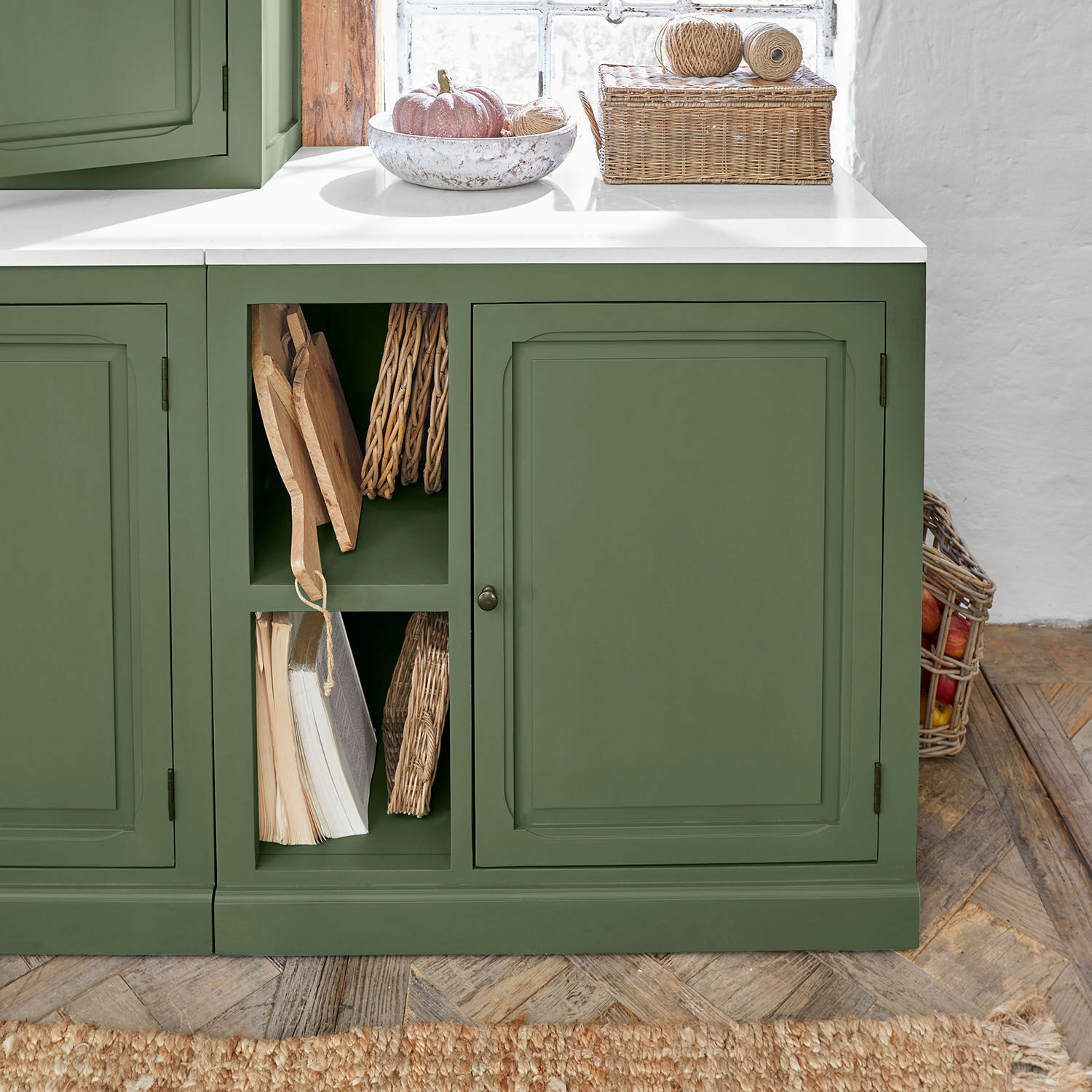 Keukenkast Lansbury Groene keukenkast met wit werkblad en open planken met boeken en rieten decoraties