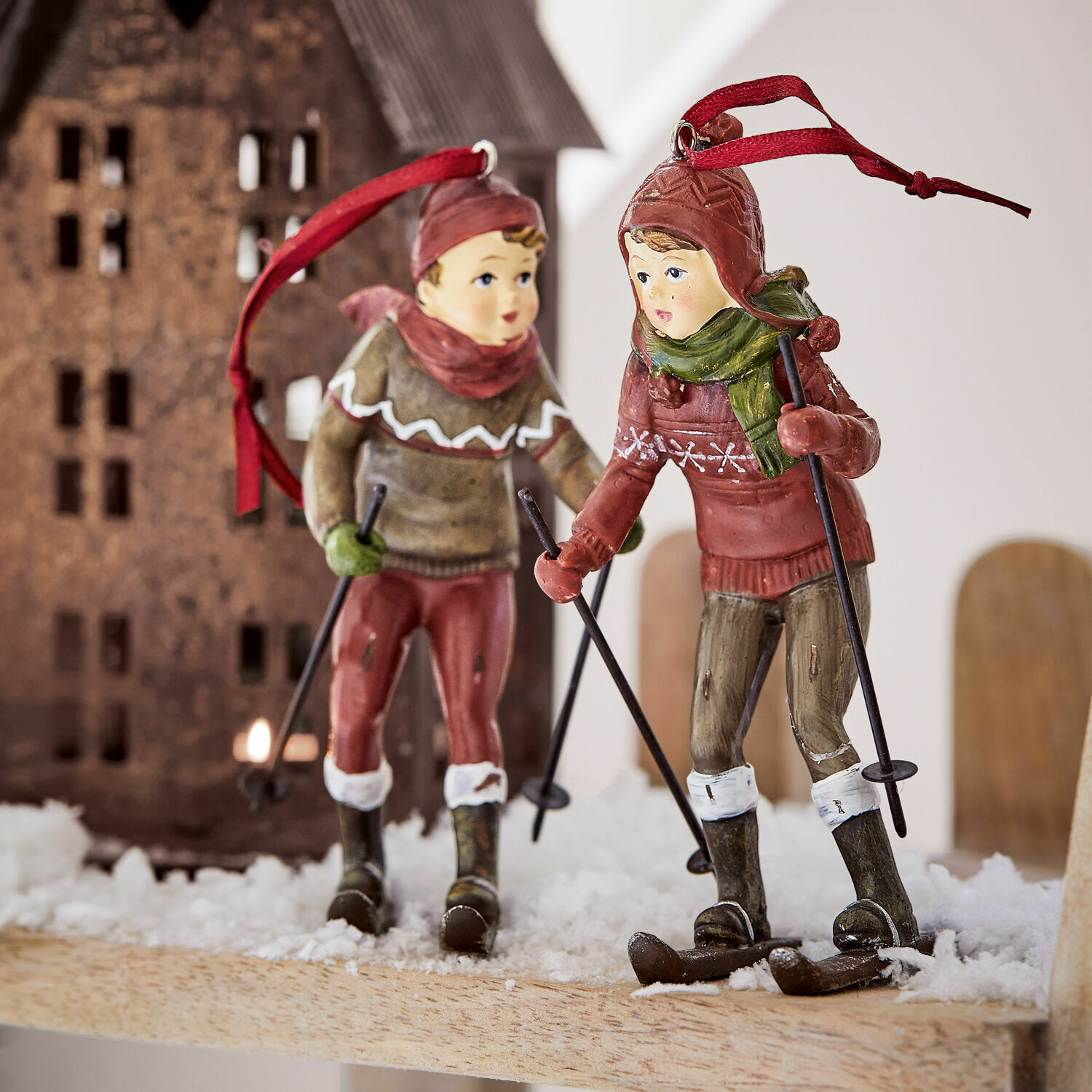 Twee skiërs decoraties van kunststof in rode en groene kleding op kunstsneeuw