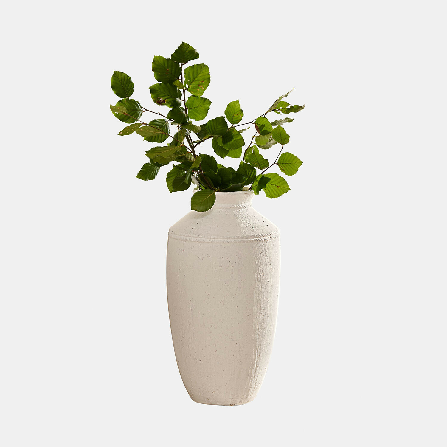 Witte keramische vaas met groene bladeren, decoratief woonaccessoire voor moderne interieurs