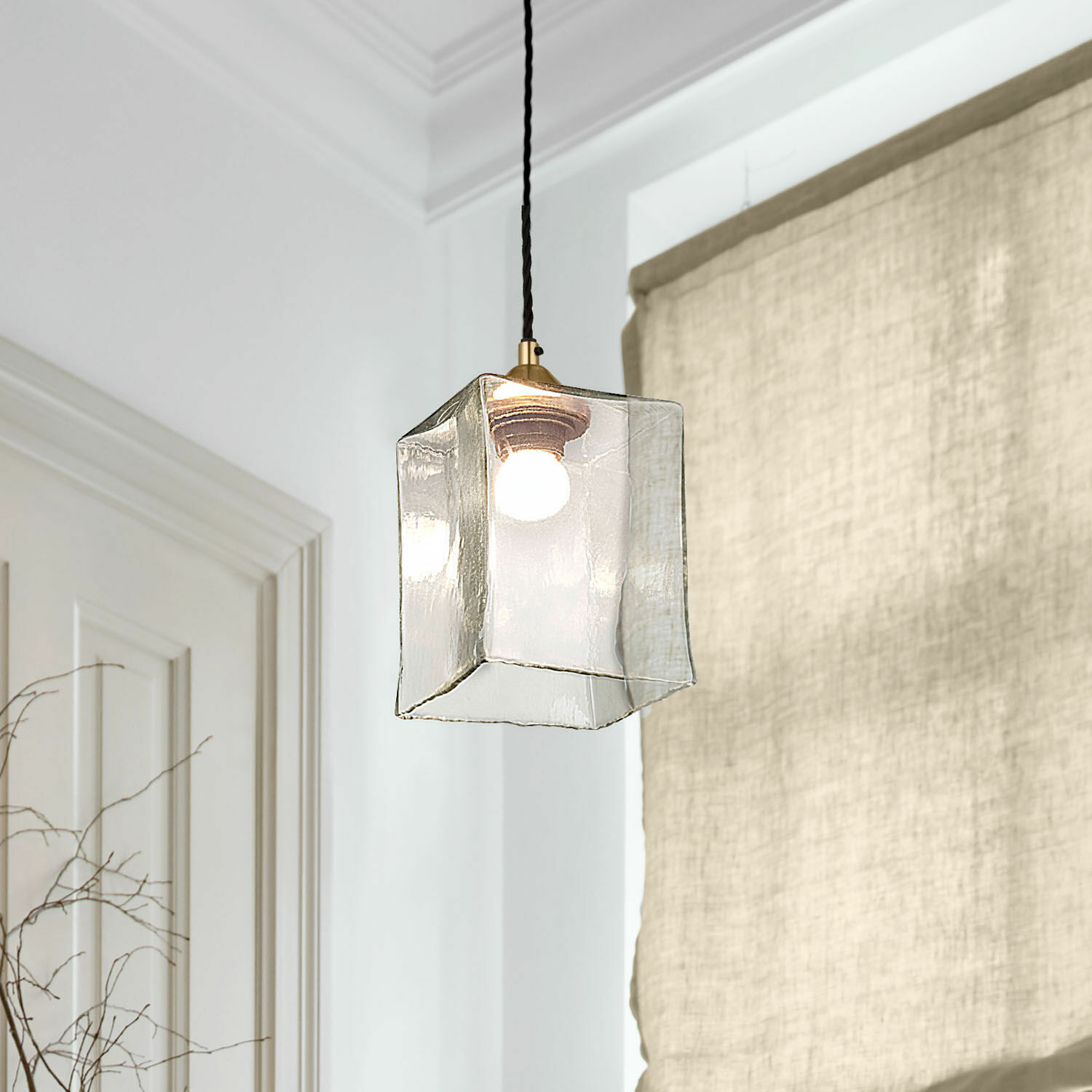 Transparante glazen hanglamp in kubusvorm met zwarte kabel en heldere lamp