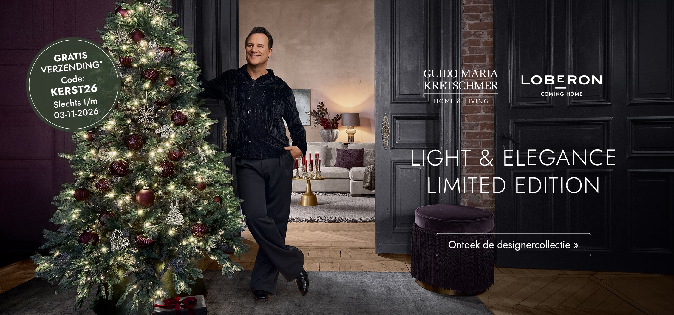Man naast verlichte kerstboom met bordeauxrode versieringen in een elegant en sfeervol interieur