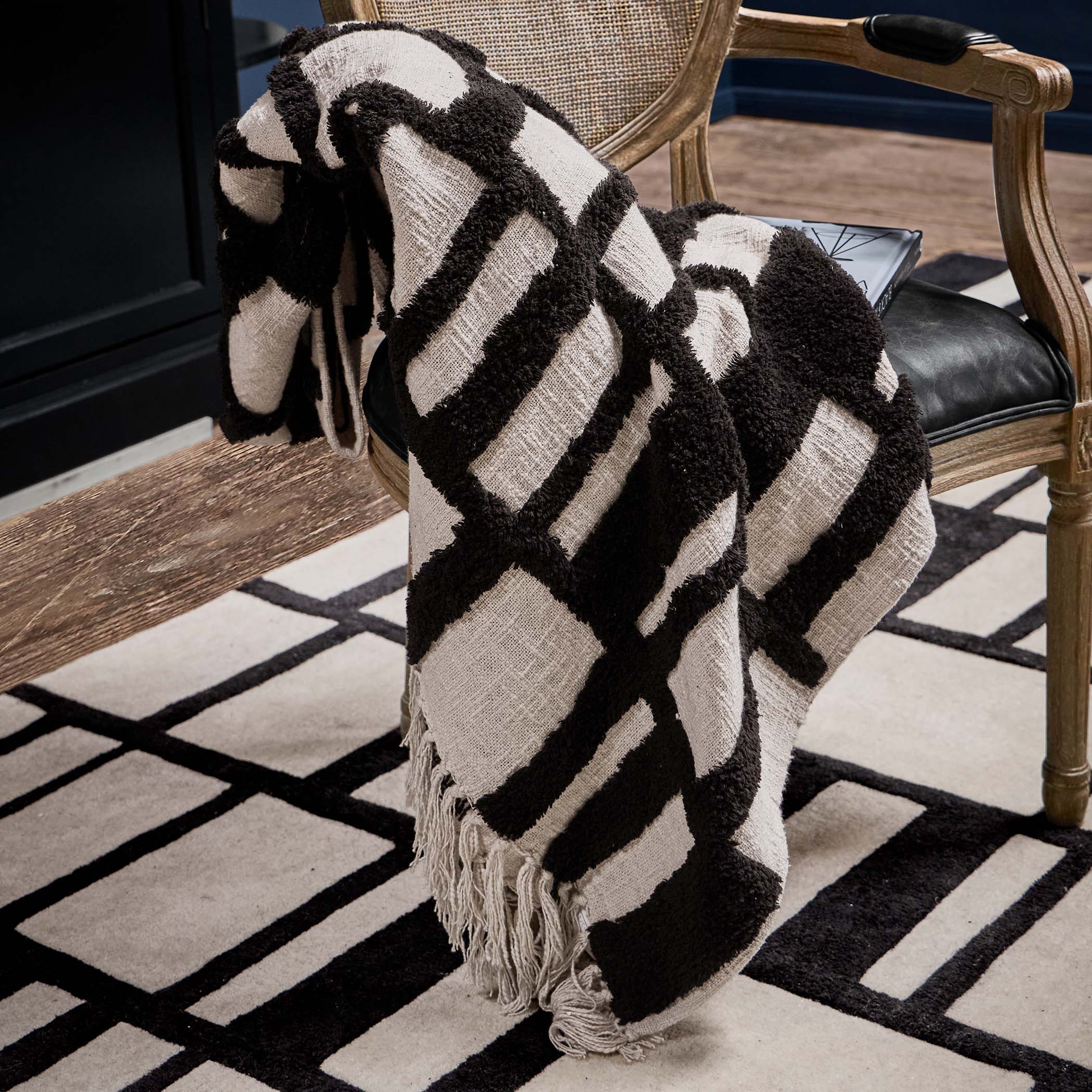 Zwart-witte plaid met geometrisch patroon van zachte stof op houten stoel in woonkamer