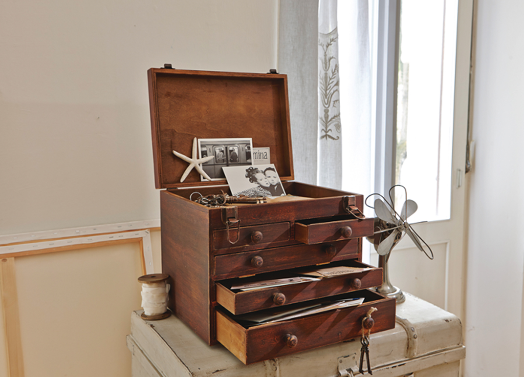 Vintage houten kist met laden en open deksel met foto’s en documenten in lichte kamer