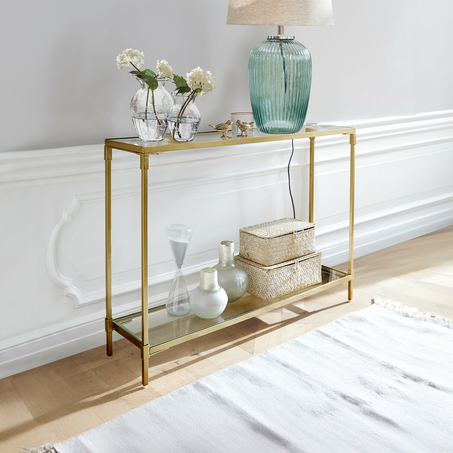 Gouden metalen sidetable met twee glazen planken, gedecoreerd met lamp en vazen, modern design