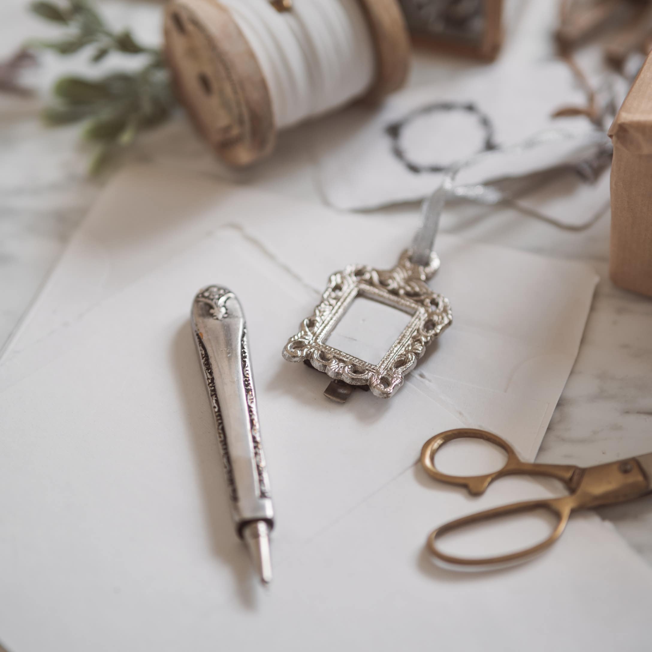 Zilverkleurige metalen clip en schrijfgereedschap op wit papier met schaar en klos garen