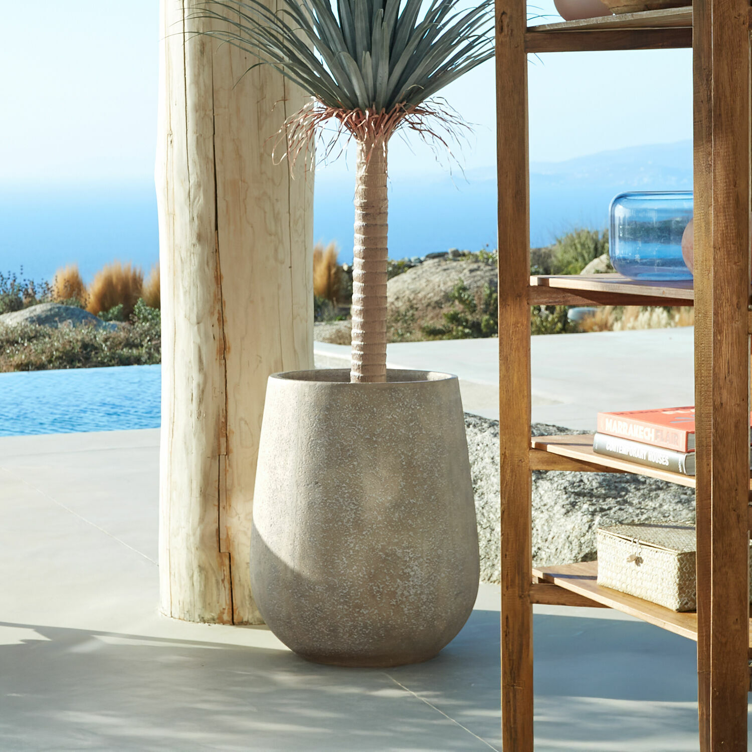 Sierpot Bressac Grote grijze betonnen pot met decoratieve plant op terras met uitzicht op zee