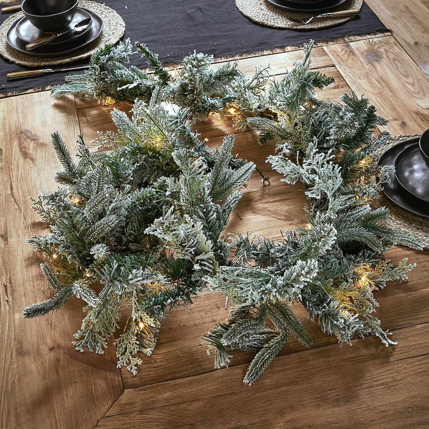 Ledguirlande Cadelise Besneeuwde kerstkrans van groene takken met zachte LED-verlichting op houten tafel
