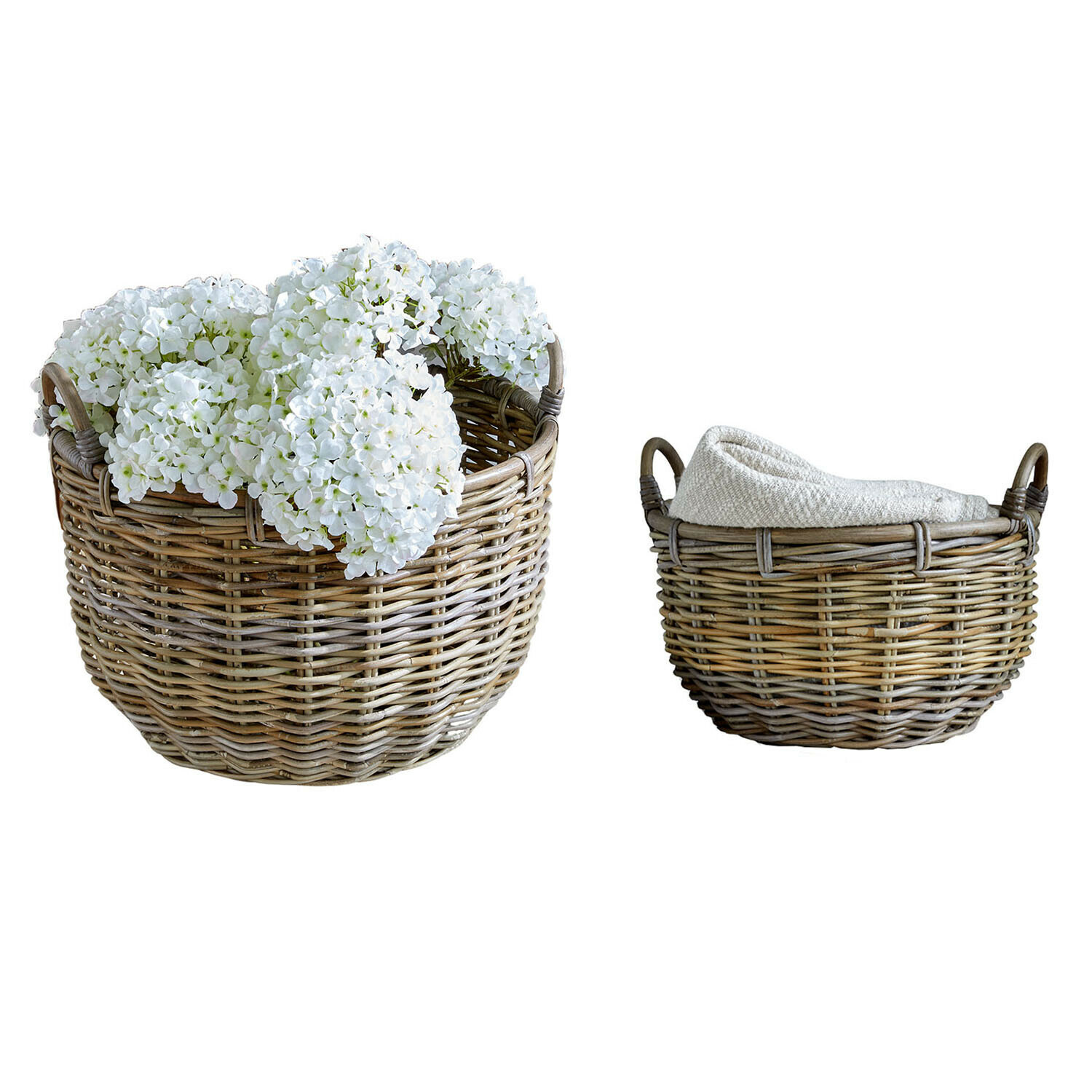 Set van twee natuurlijke rieten manden, één met witte bloemen, de ander met gevouwen stof