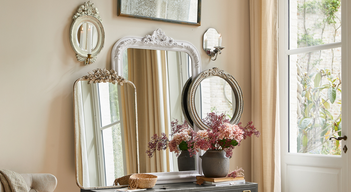 Set decoratieve spiegels met versierde lijsten in lichte kamer met bloemen en kaarsen