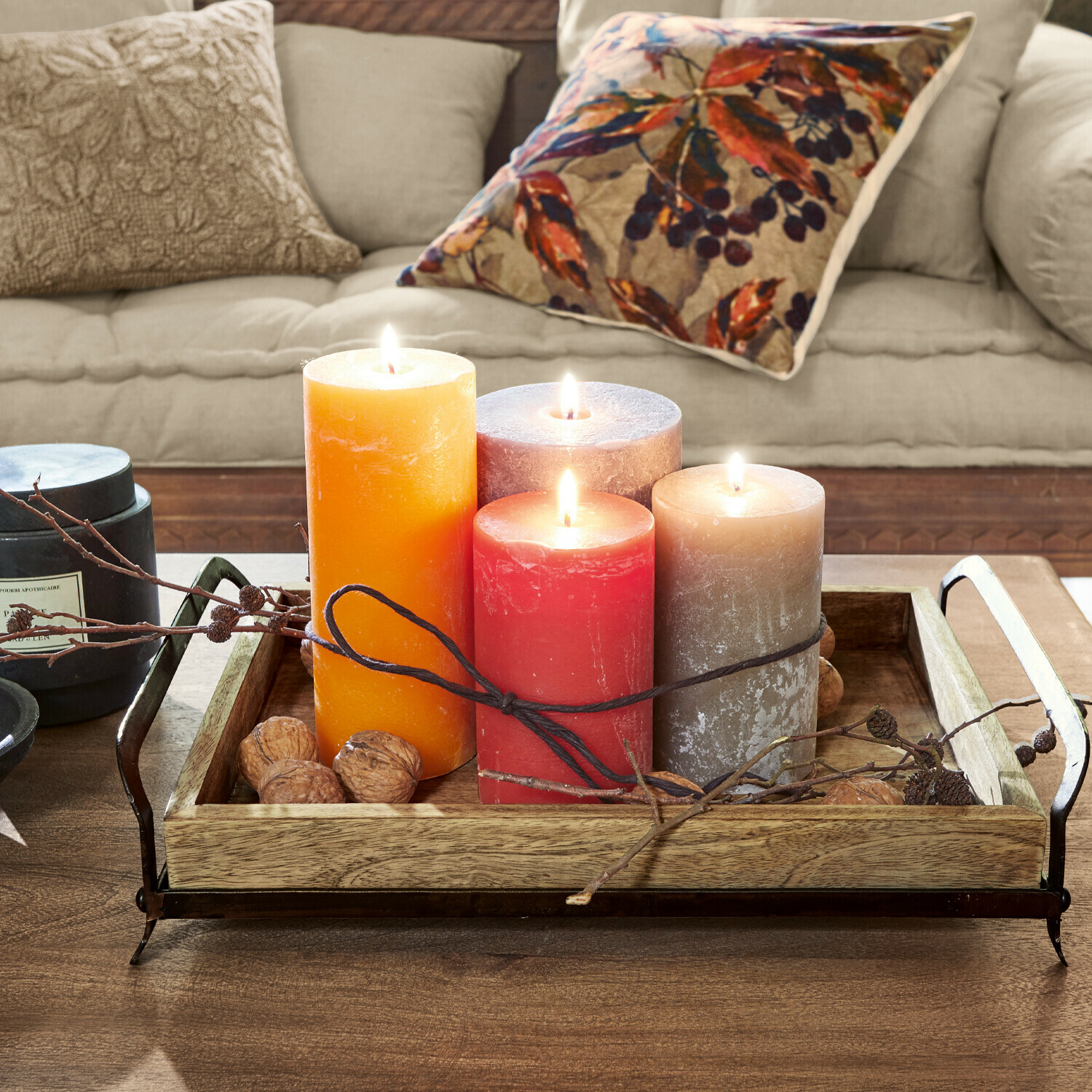 Vier gekleurde kaarsen op een houten dienblad met metalen handvatten op een houten tafel