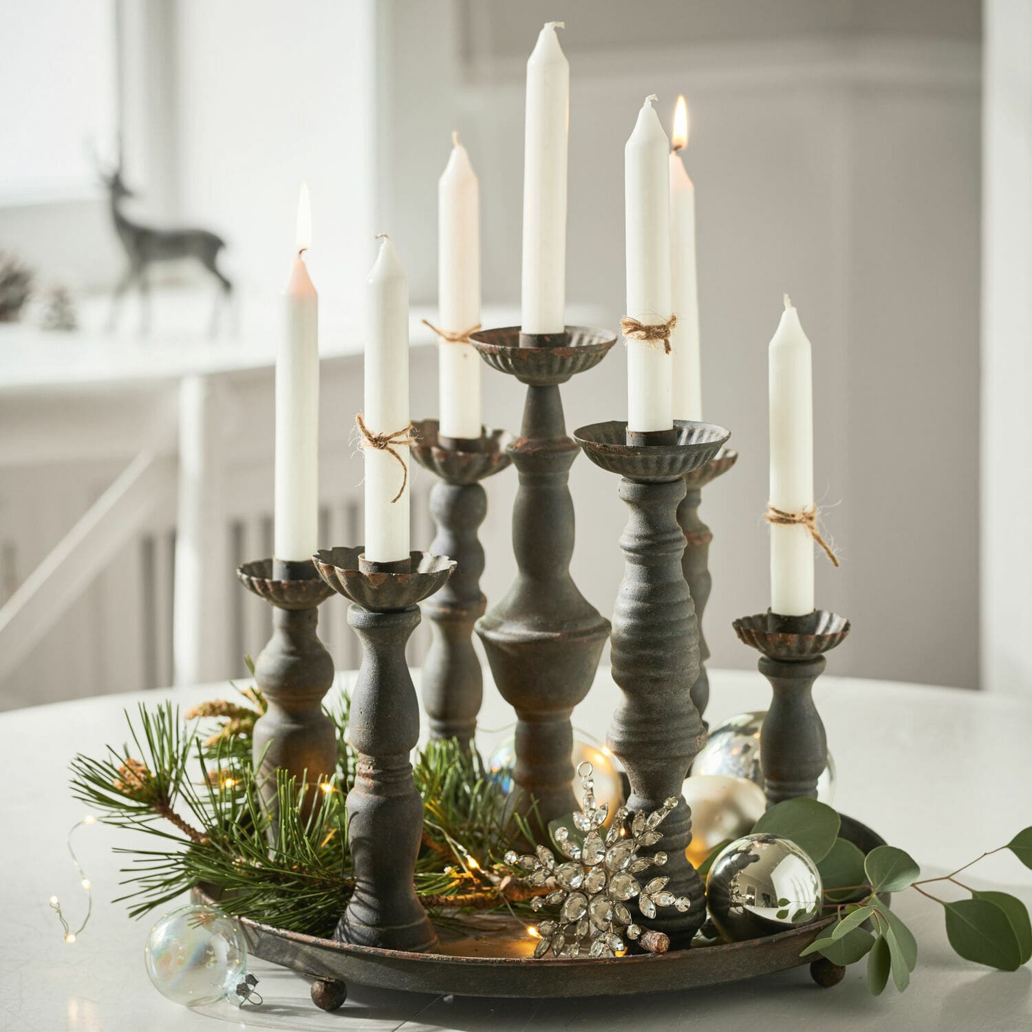 Metalen kandelaar met acht witte kaarsen en kerstdecoraties op een ronde schaal