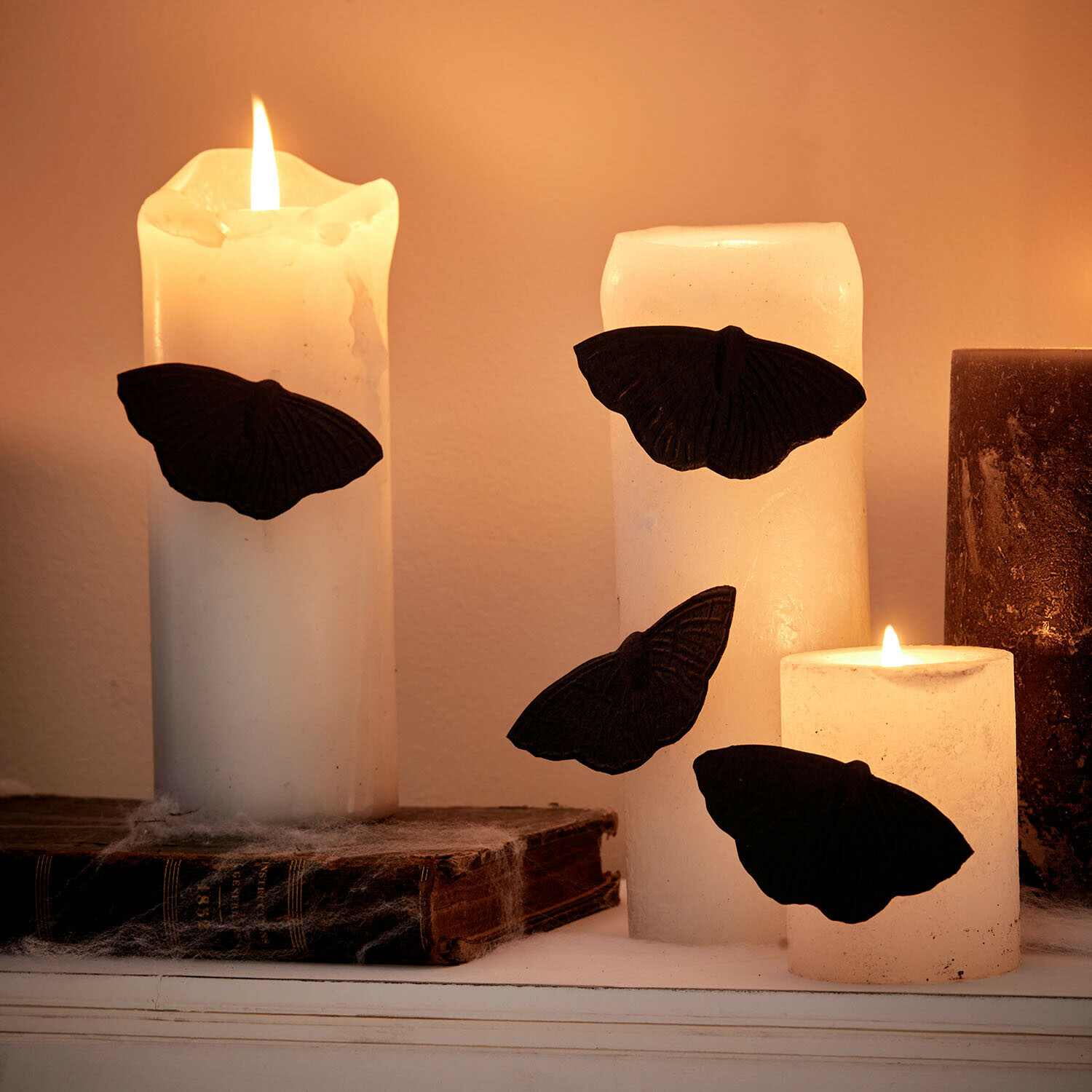 Decoratiepin set van 4 Orlenaith Witte kaarsen met zwarte vlinderdecoraties op oude boeken, sfeervolle verlichting