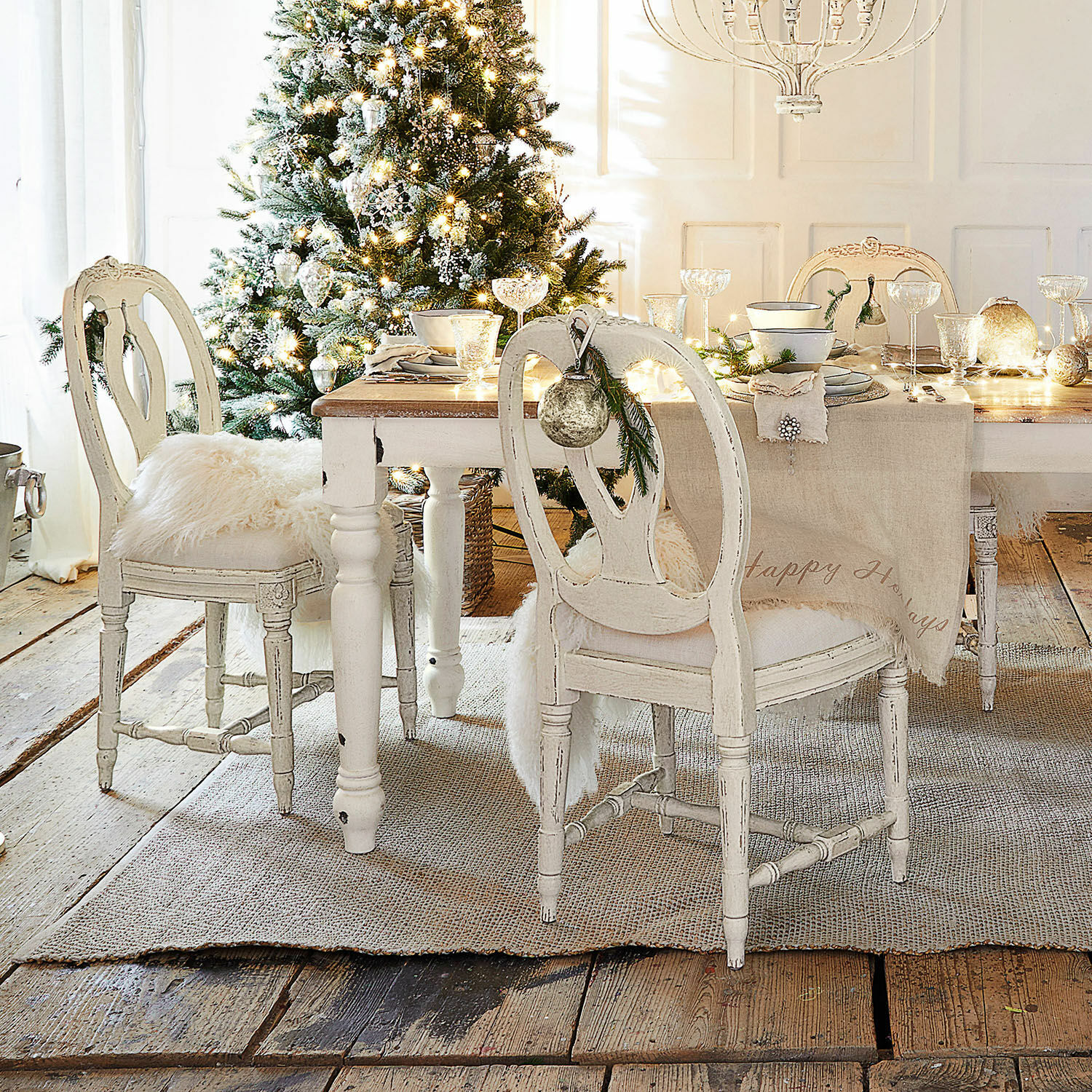 Eetkamer met witte houten tafel en vintage stoelen feestelijk versierd voor Kerstmis