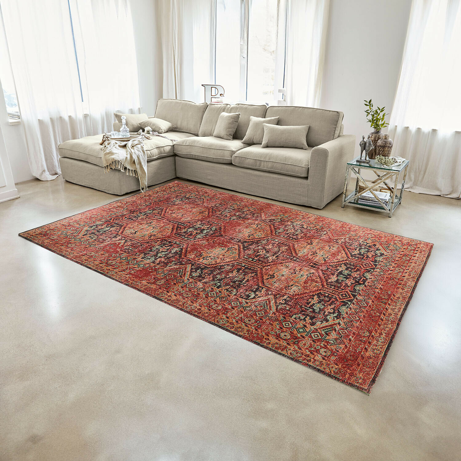 Rode vloerkleed met oosters patroon op lichte vloer in moderne woonkamer met beige bank