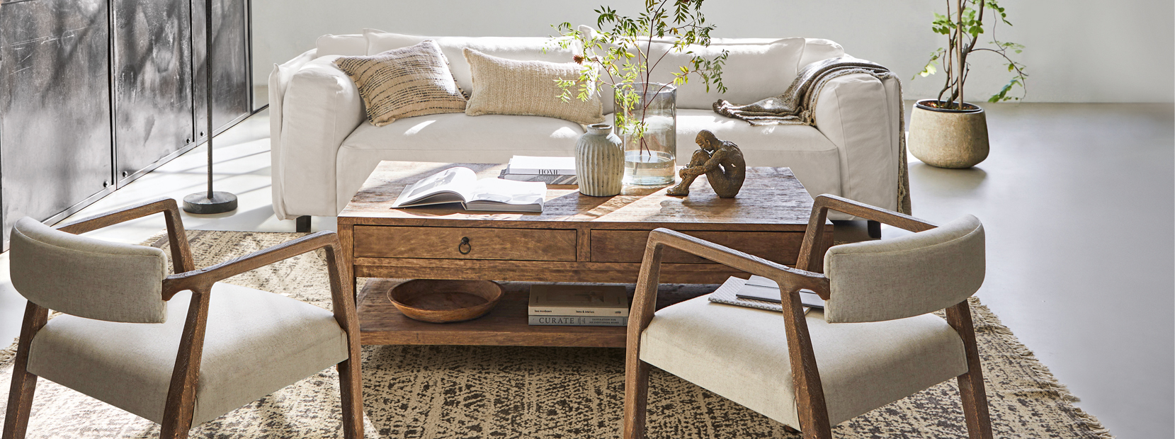 Woonkamer met witte bank, houten salontafel en beige fauteuils in loftstijl met decoraties
