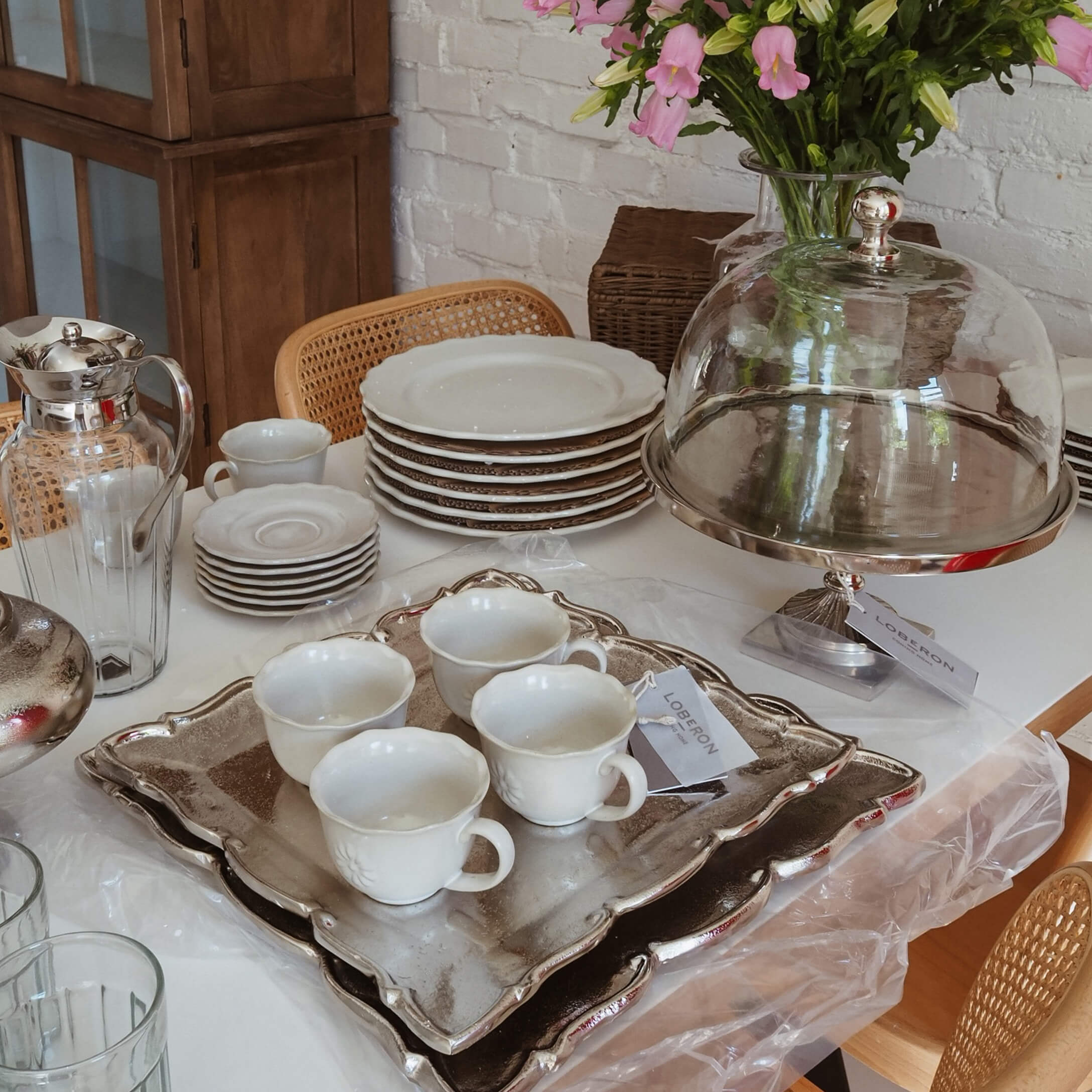 Witte porseleinen set met kopjes en borden op zilveren dienblad, slow living tafeldecoratie