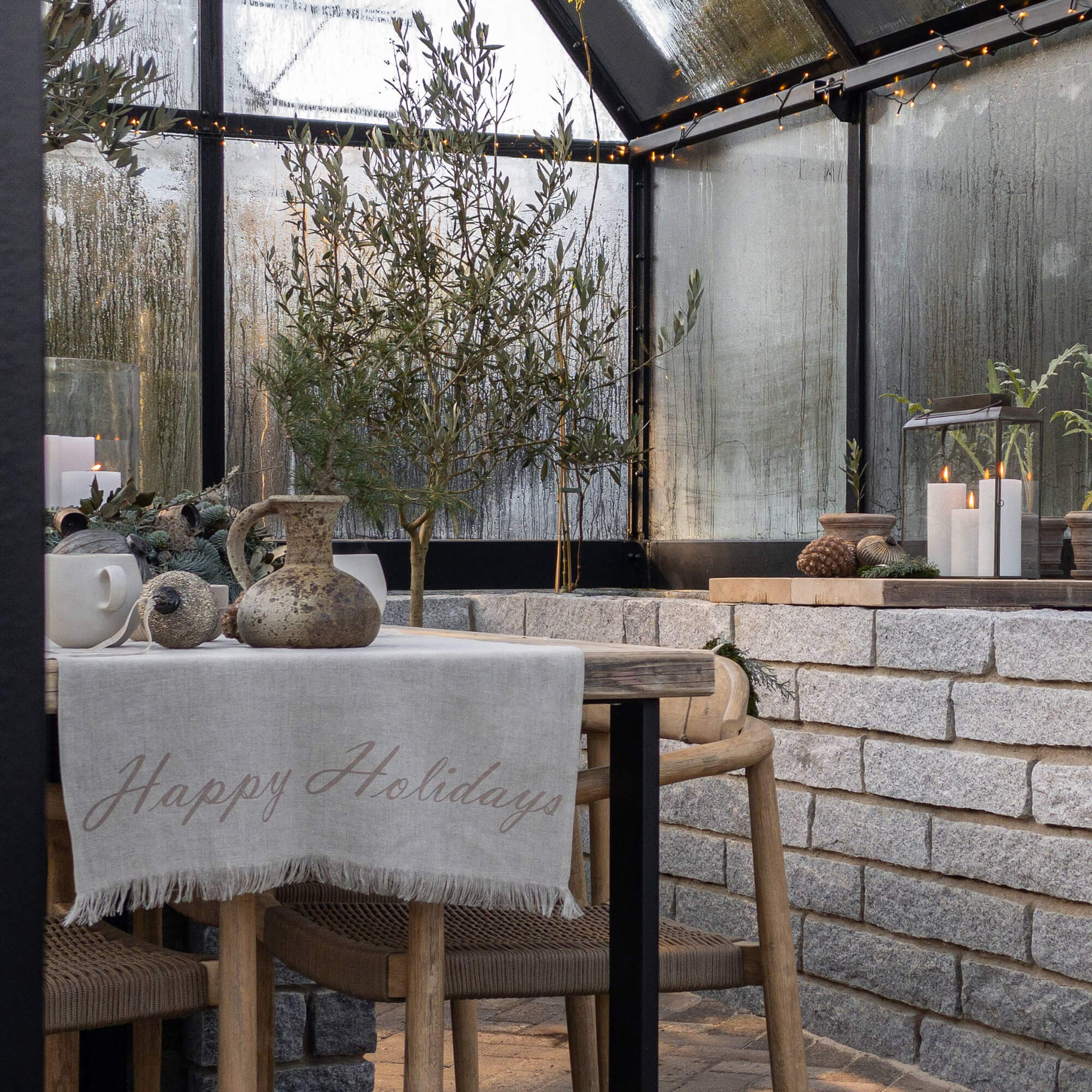 Gezellige hoek met houten tafel, linnen tafelkleed en kerstdecoratie in een kas
